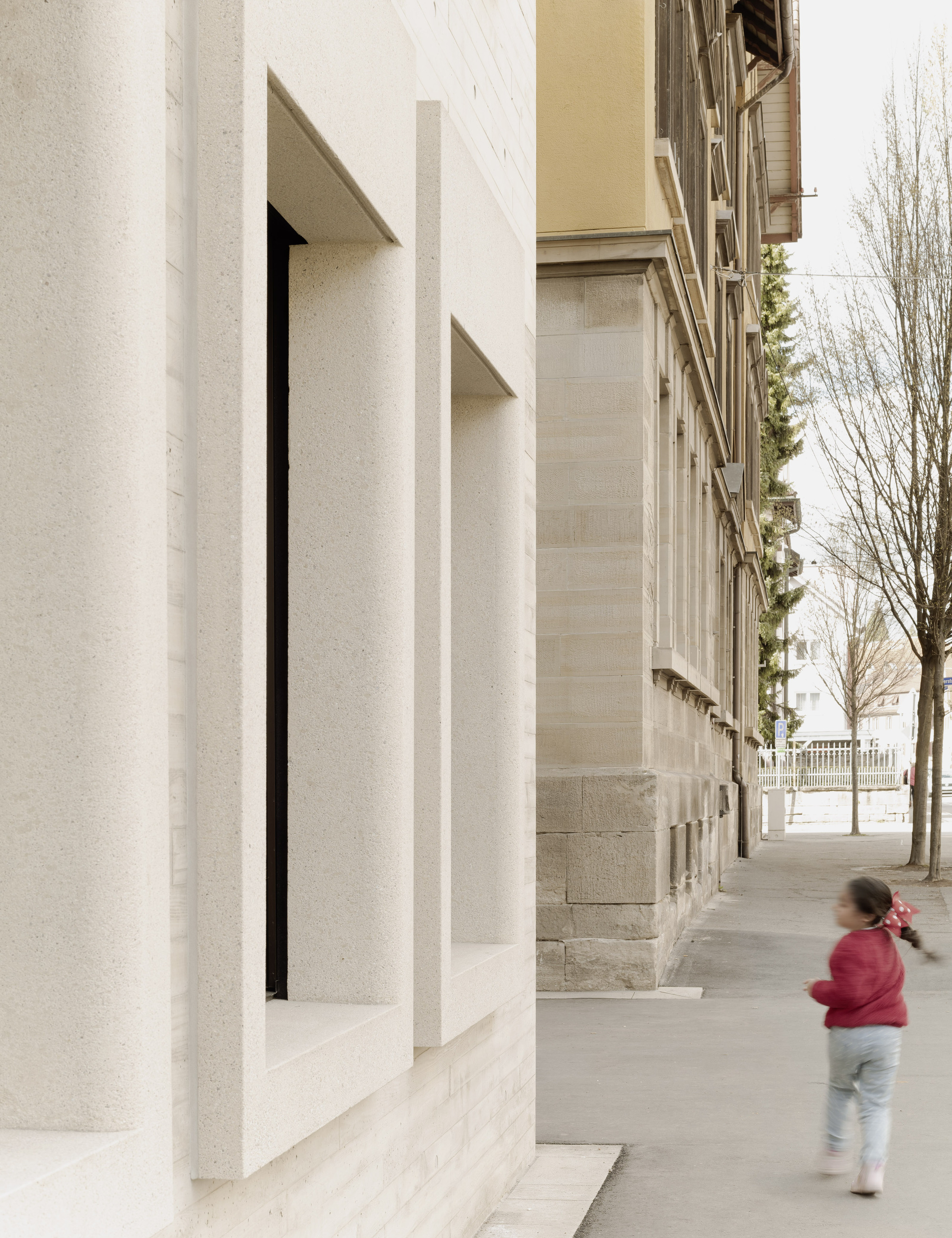 Deep window reveal at ground level with a child walking past on the sidewalk