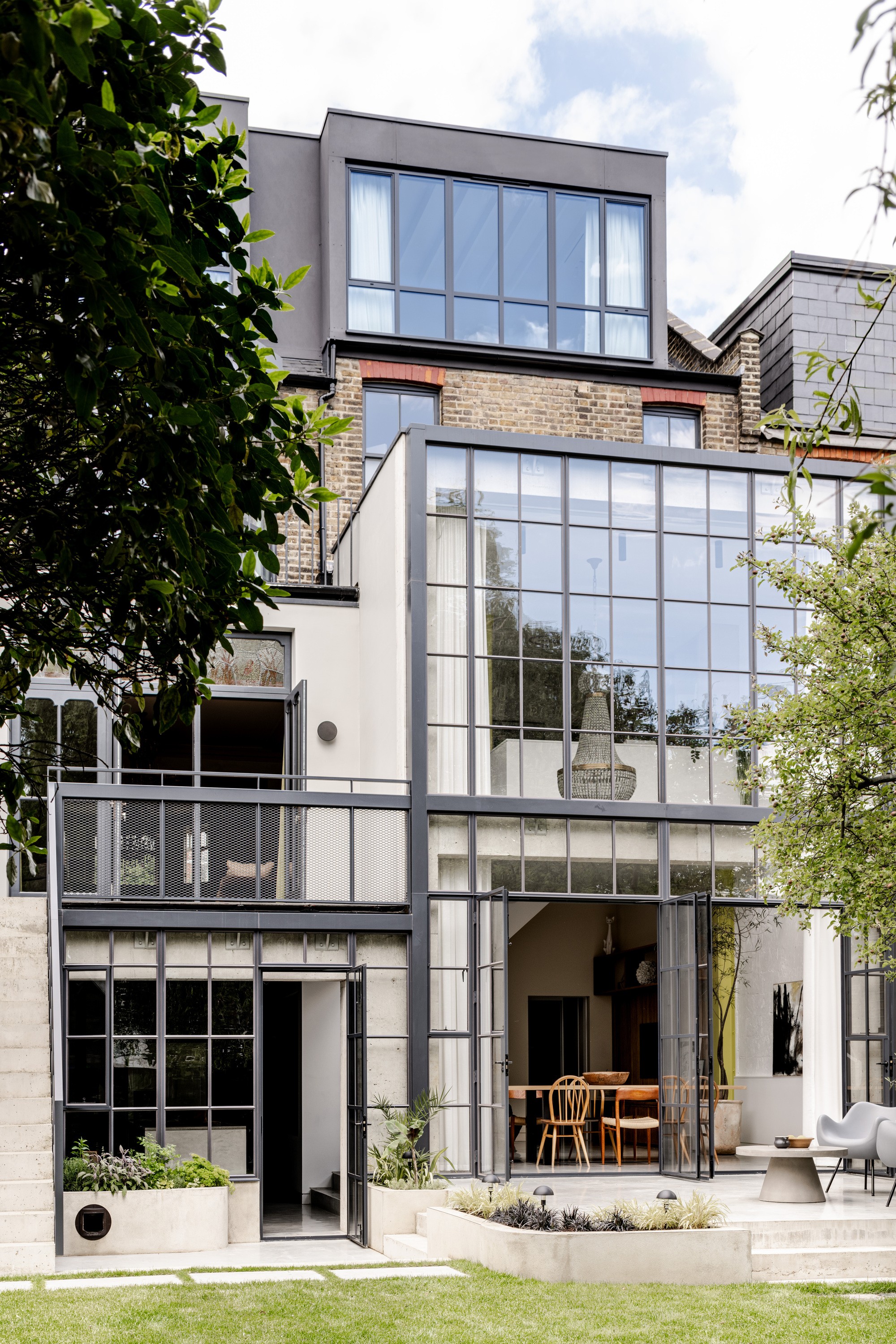 Rear facade with stacked steel-framed glazing and balcony opening to lawn and garden