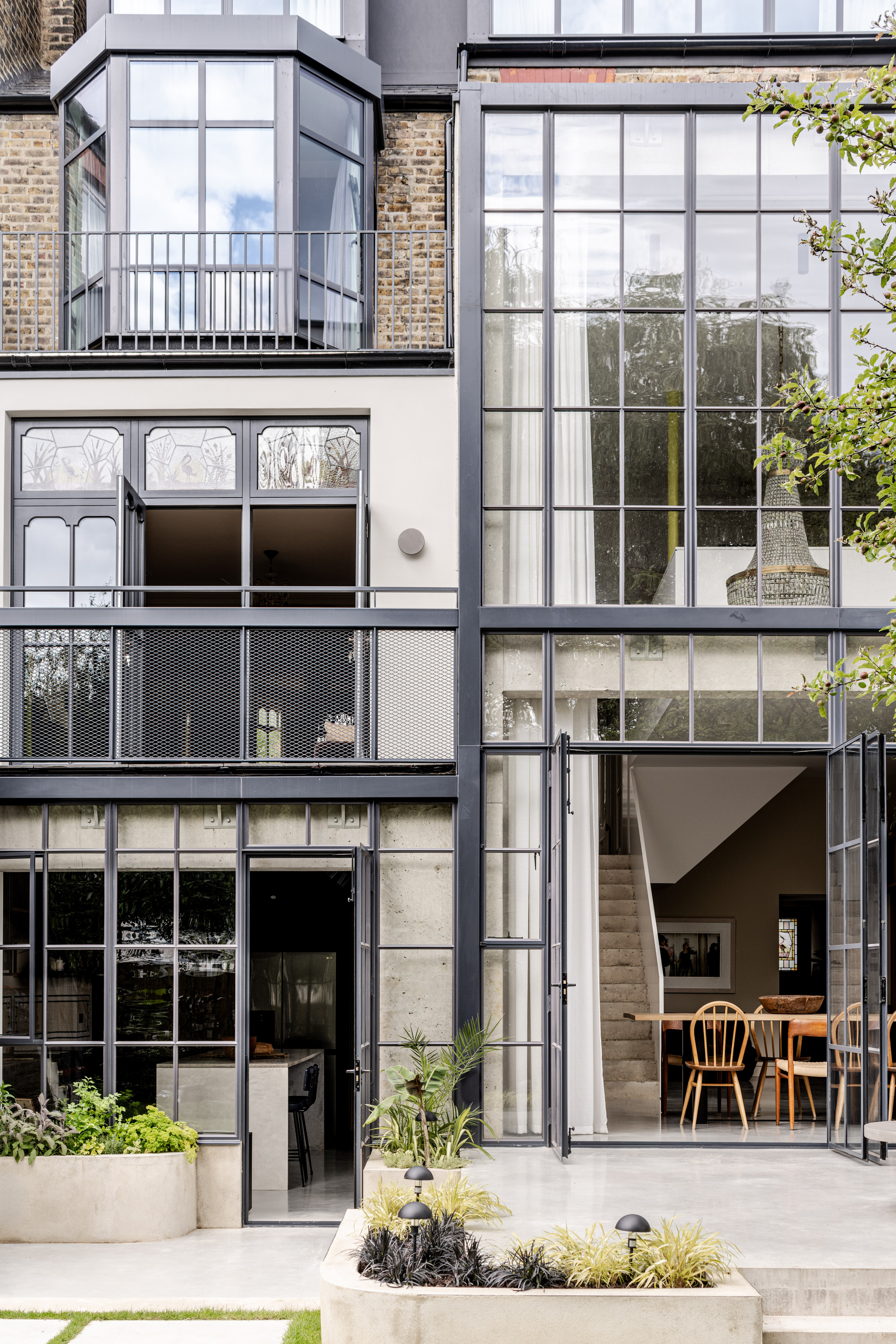 Rear facade showing stacked volumes with steel frame glazing, concrete balconies and ornamental glass panels
