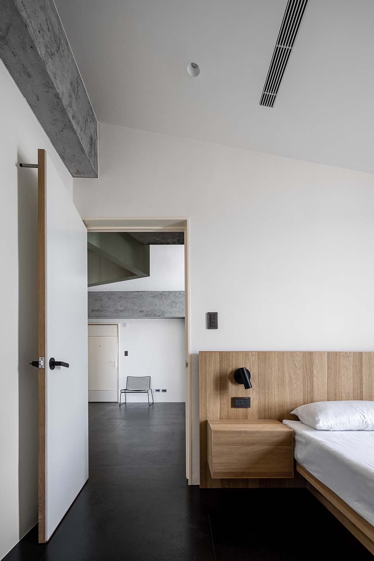 Bedroom with timber platform bed and view through doorway to adjacent spaces
