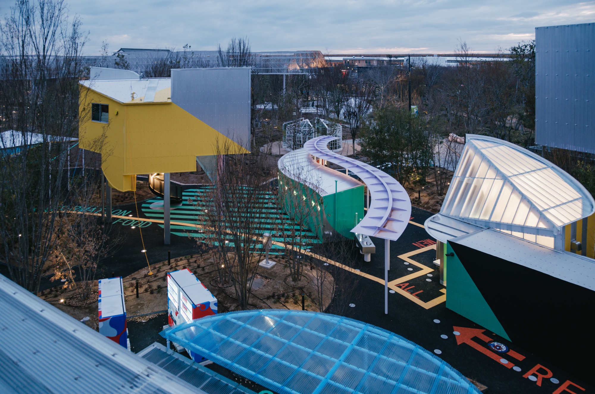 Aerial view of the multi-colored pavilion cluster with corrugated roofs at dusk