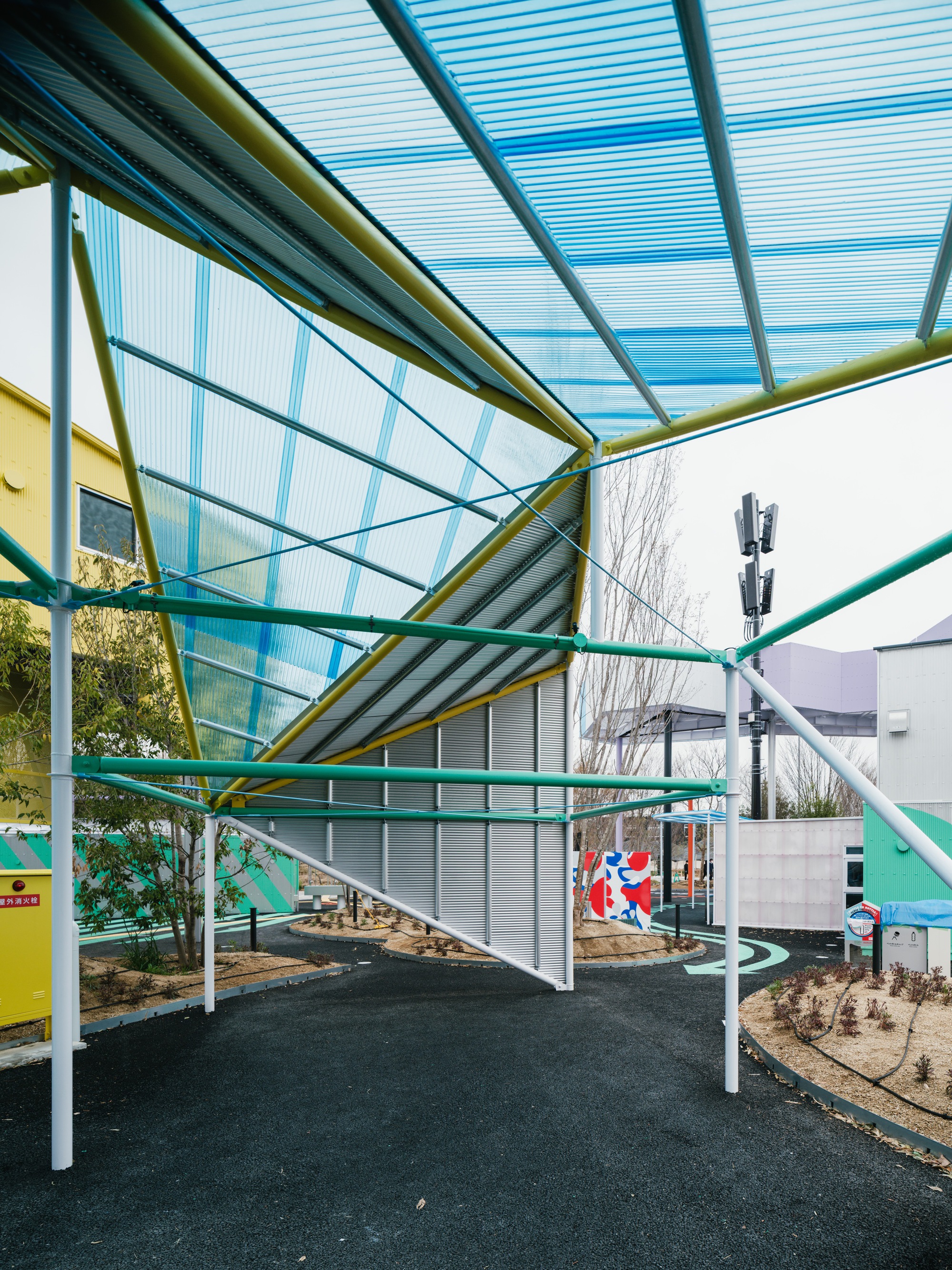 View beneath the translucent polycarbonate canopy supported by yellow and green steel trusses