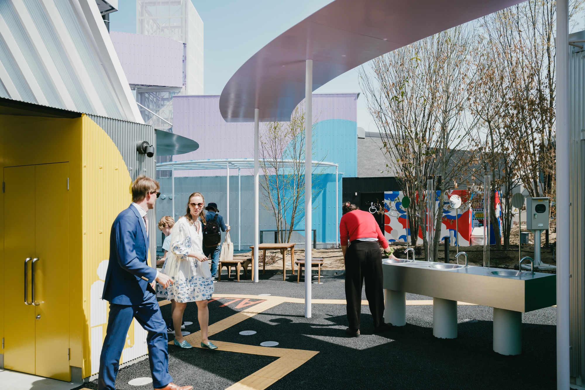 View of the courtyard with visitors gathering around play elements under translucent canopy and bare trees