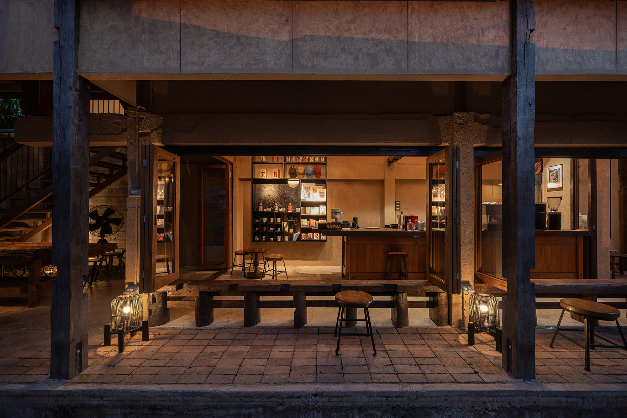 Street view of the open pavilion framed by timber columns with dining platform and interior bar at twilight