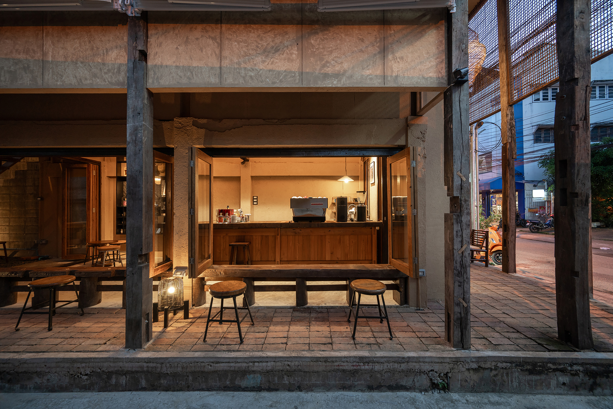 Open storefront with timber counter, exposed structural columns and overhead beams at dusk