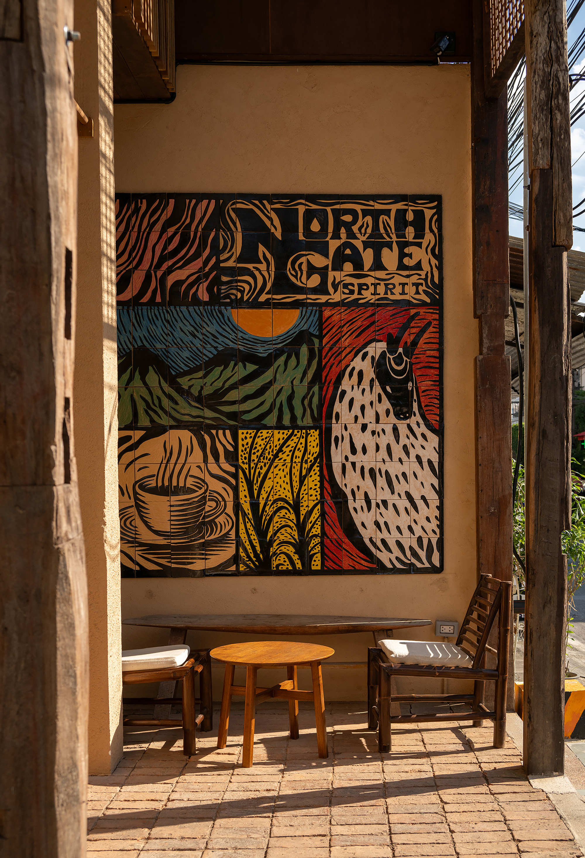 Interior courtyard seating area with mural and timber frame in morning sunlight