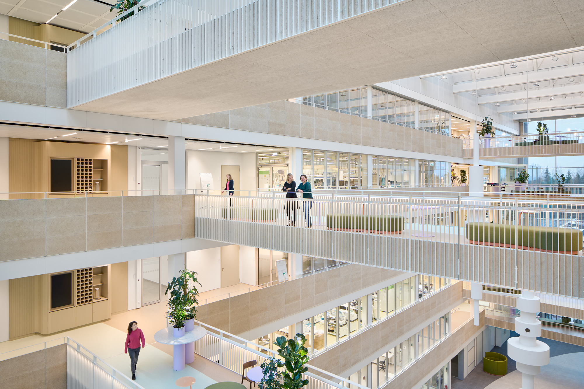 Walkway with white vertical railings and two people overlooking the atrium below