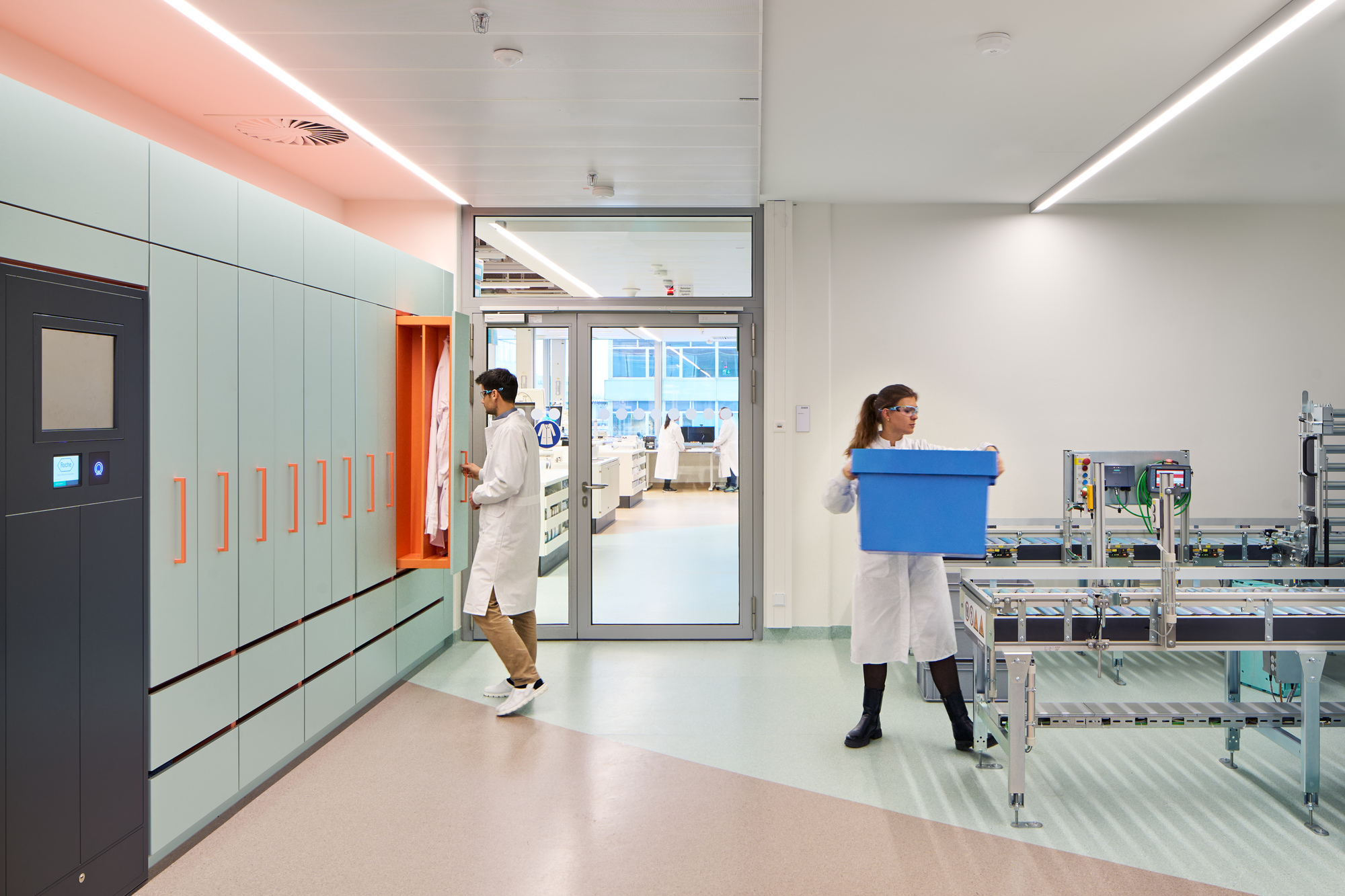 Laboratory corridor with pale blue lockers, orange handles and two researchers in white coats