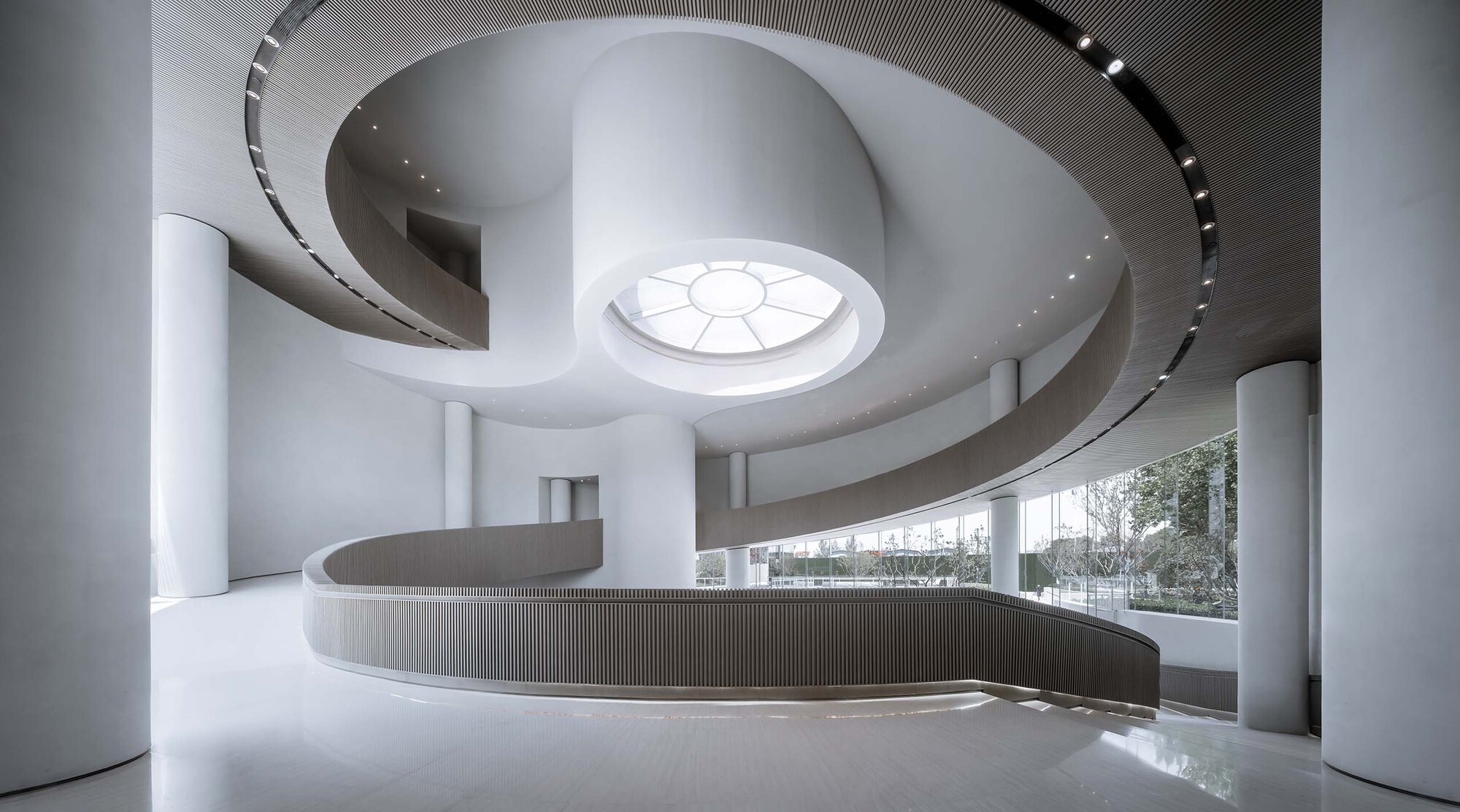 Spiraling interior staircase with vertical fin balustrade and circular skylight overhead