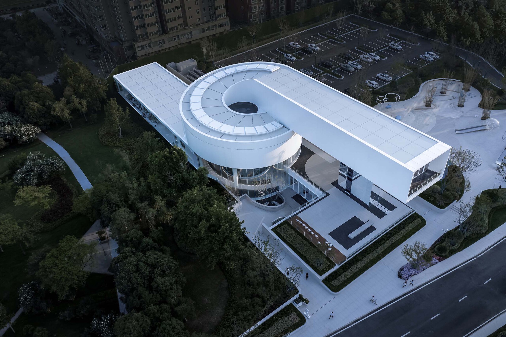 Drone view of the spiral roof form with central oculus and adjacent parking lot