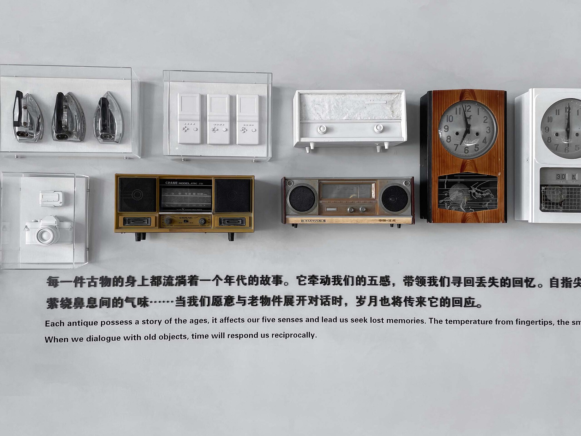 Display shelf of vintage radios and clocks mounted on white wall with descriptive text below