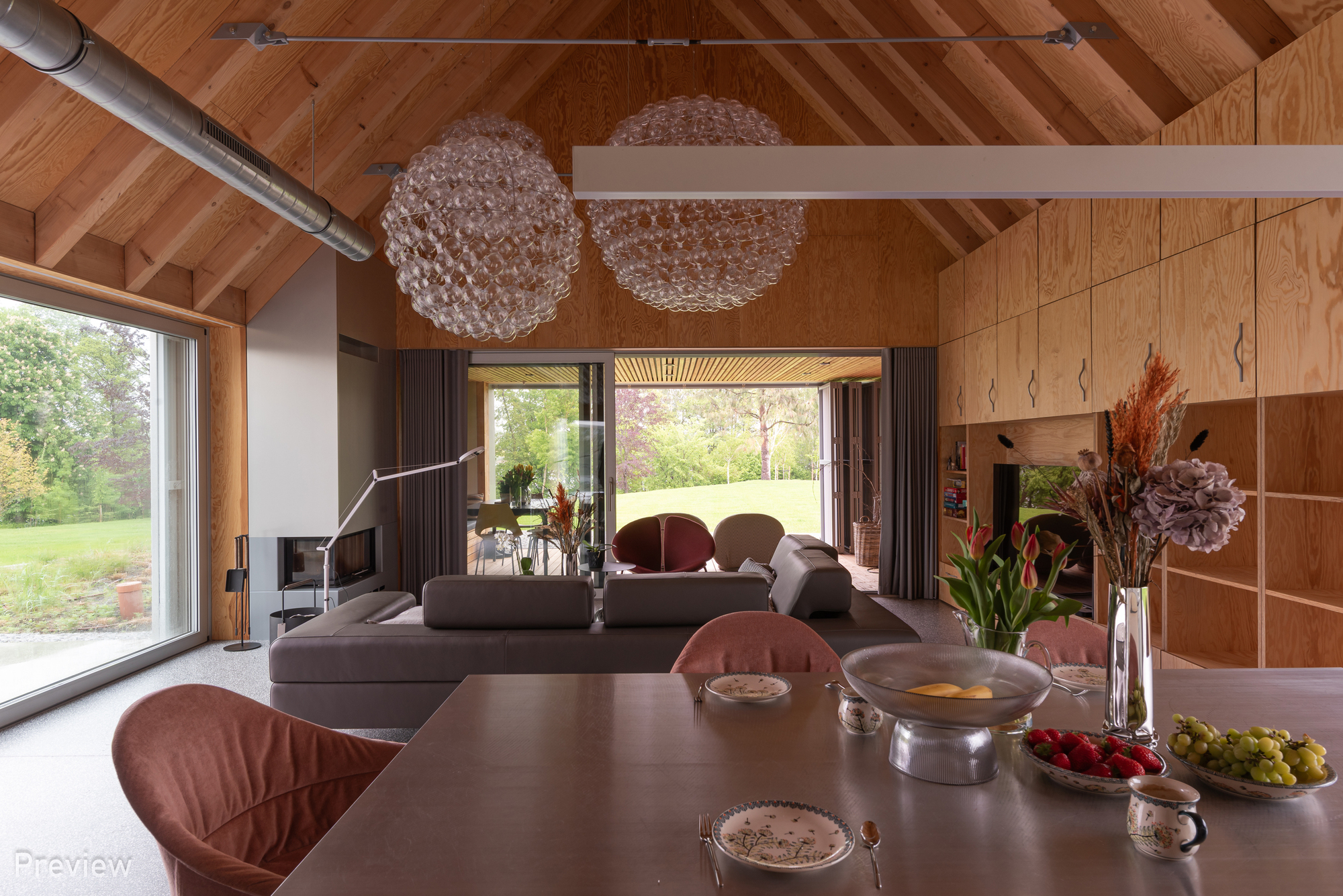 Dining table view toward living area with folding glass doors opening to lawn