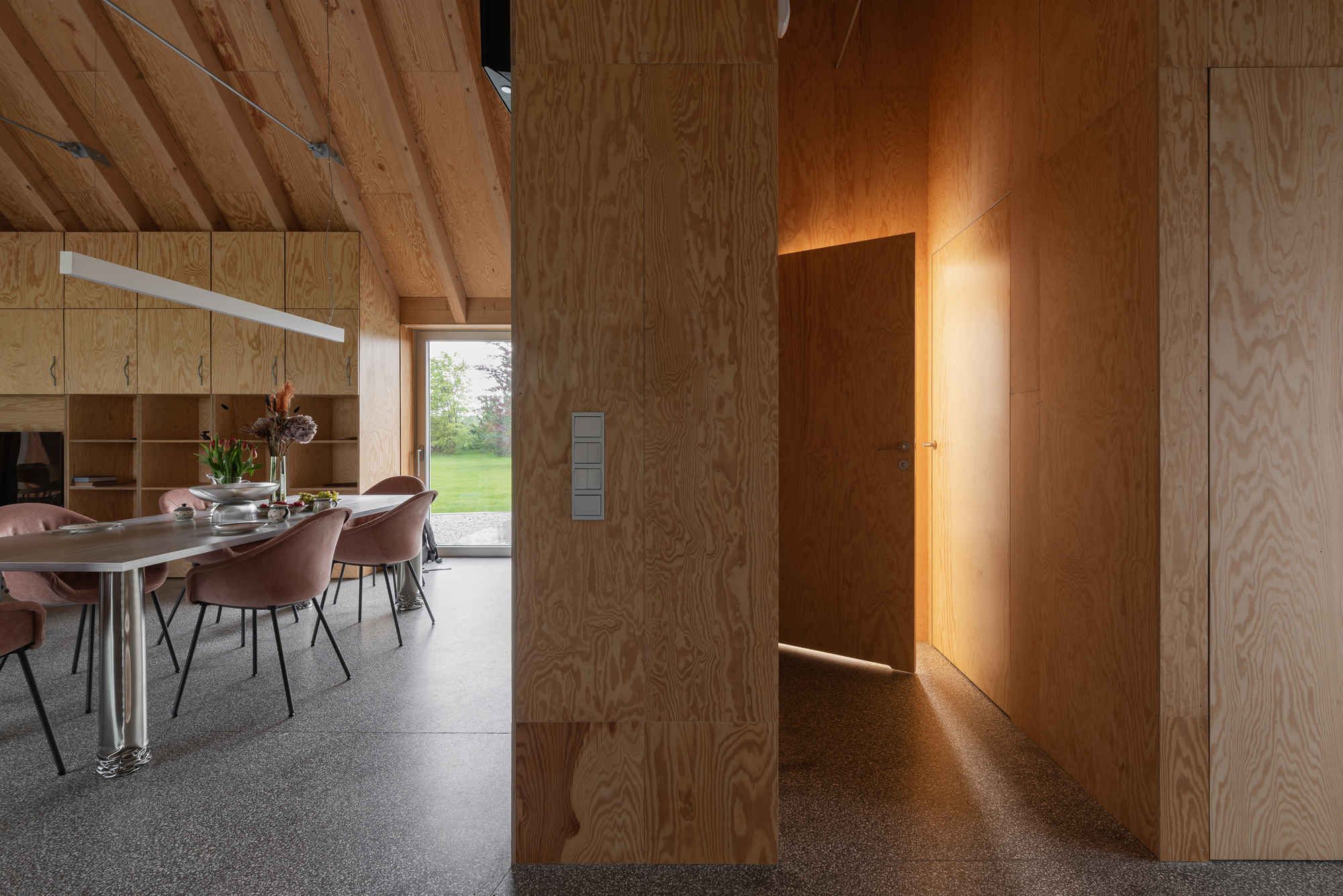 Plywood clad corridor with warm concealed lighting at door jambs and ceiling