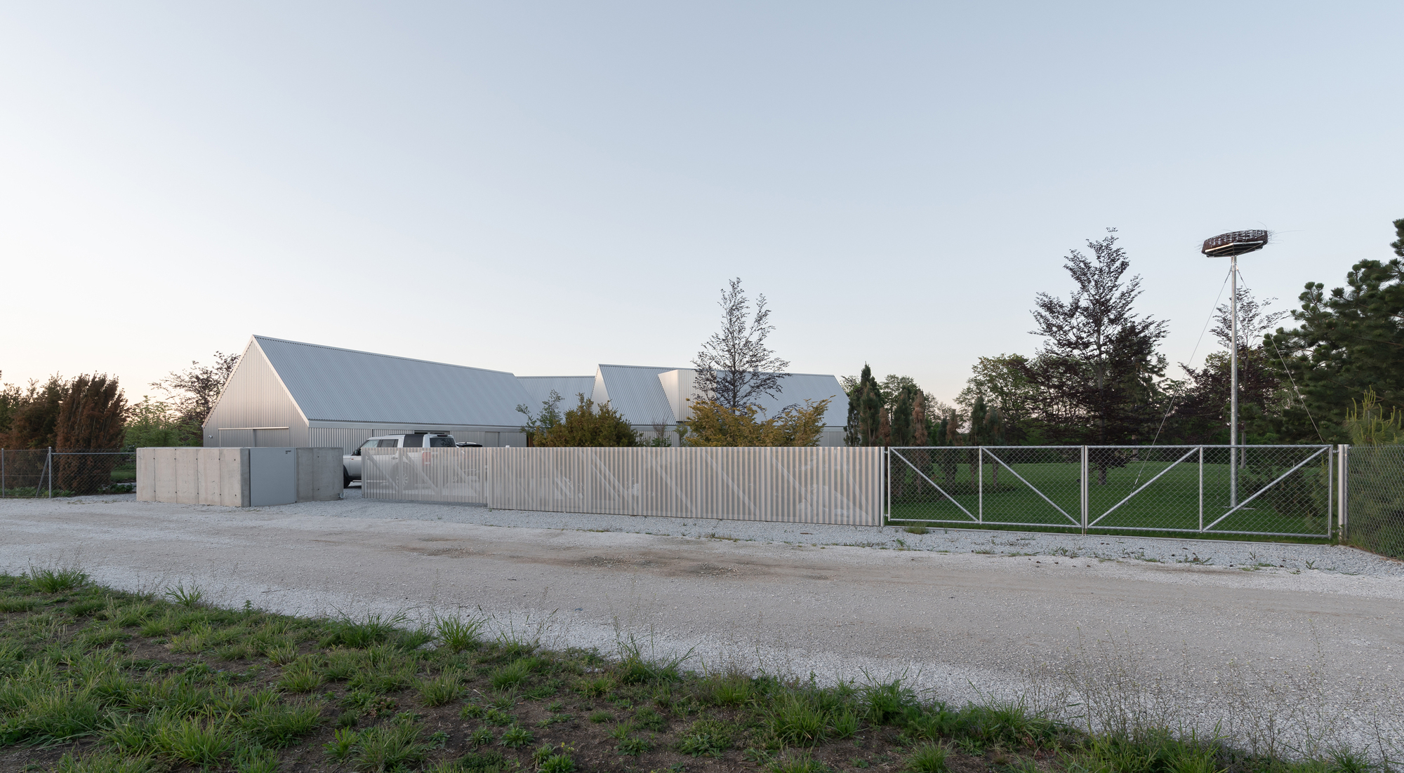 Street view of vertical timber fence and pitched metal roofs at dusk