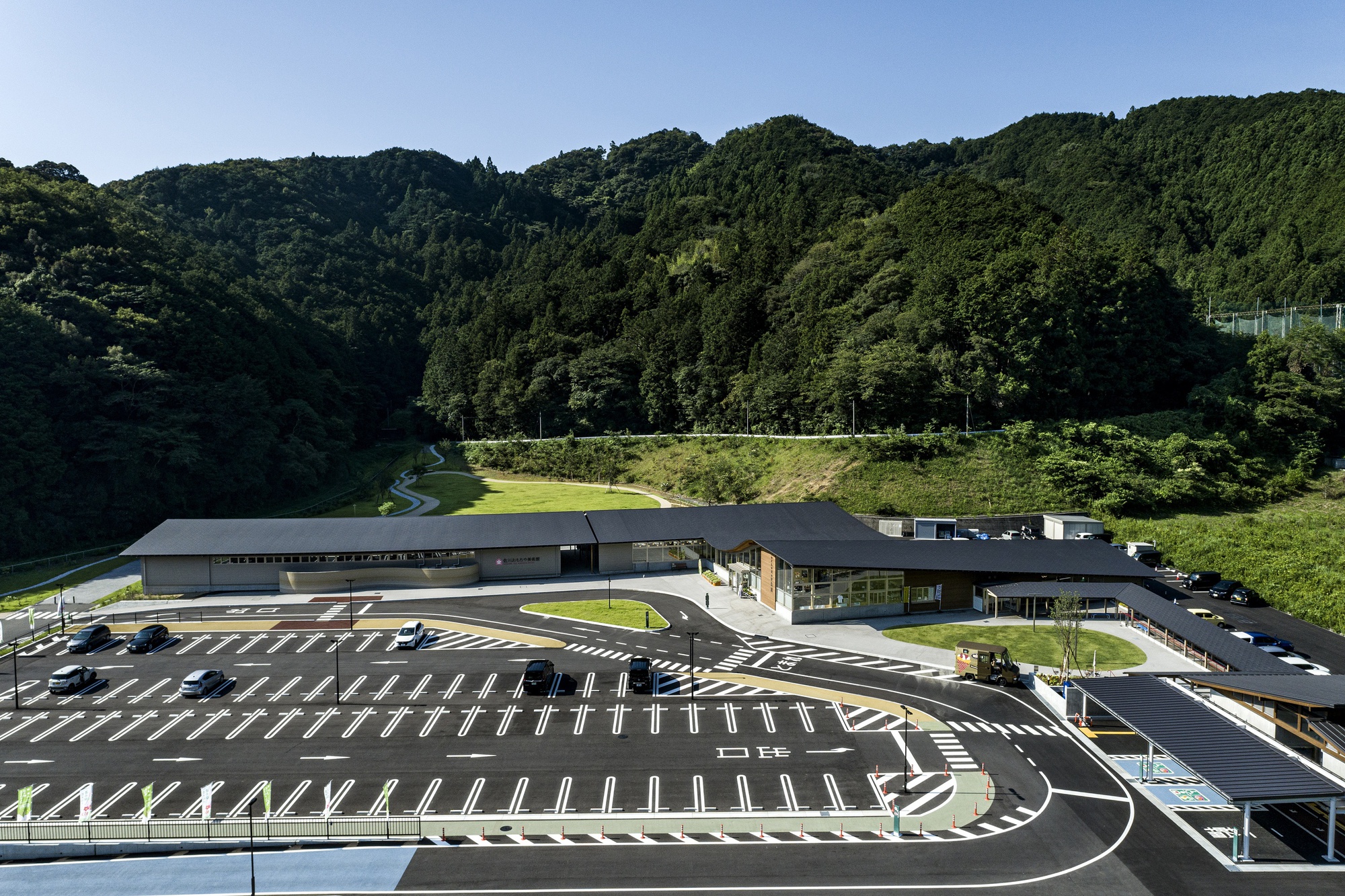 Aerial view of the curved complex with parking lot and forested mountain valley beyond