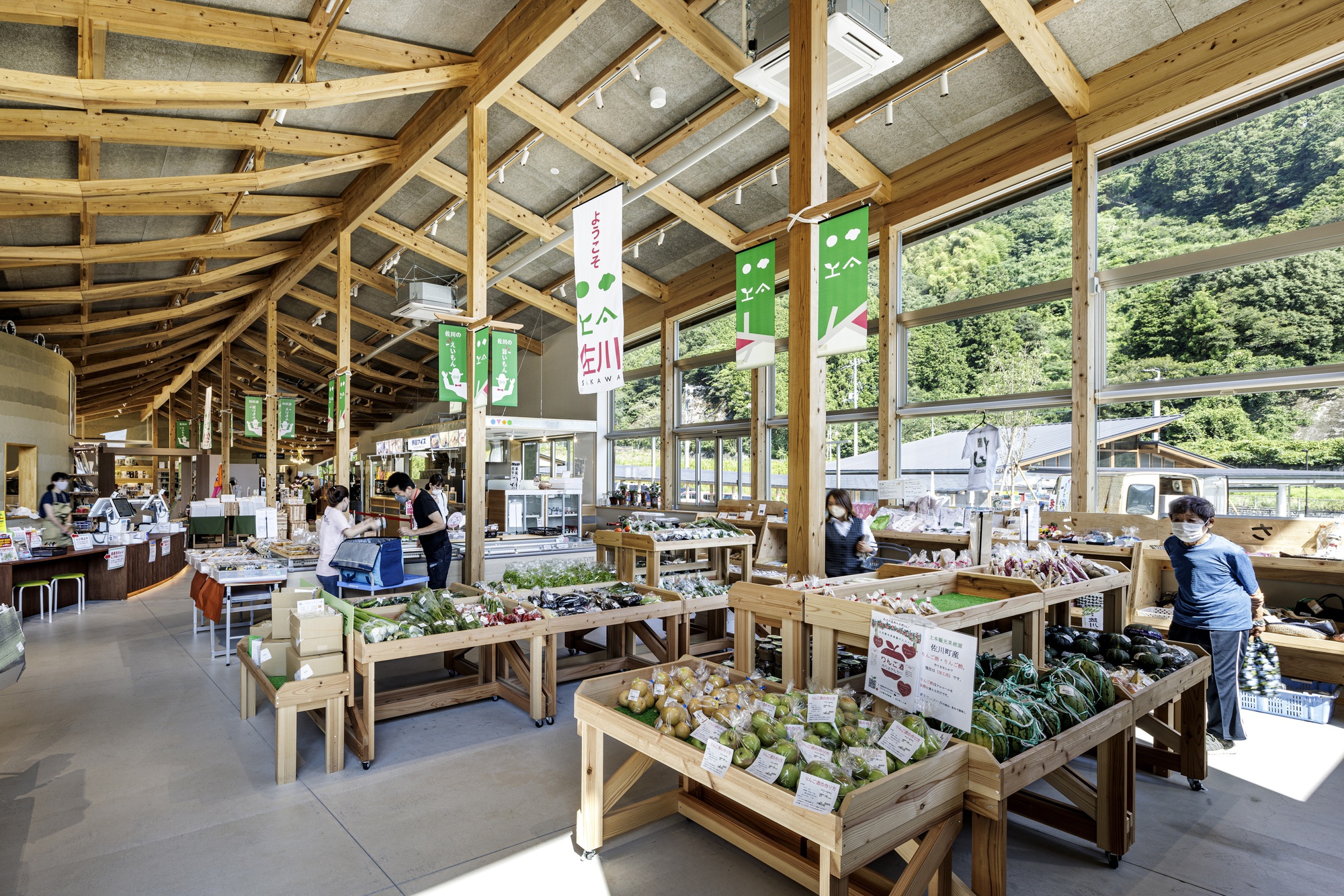 Market hall with timber roof structure and produce display tables beneath colorful hanging banners