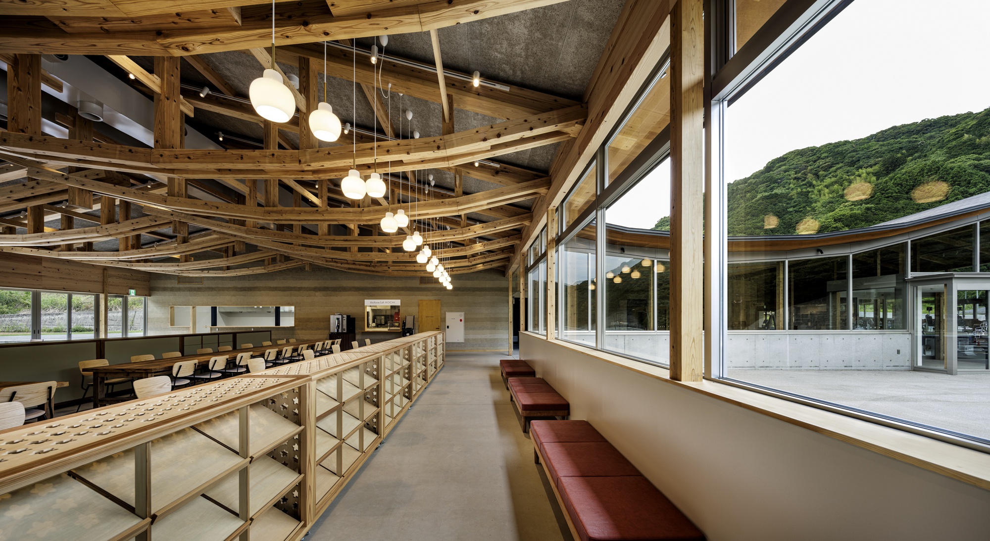 Corridor with curved timber ceiling beams and built-in seating along a window wall