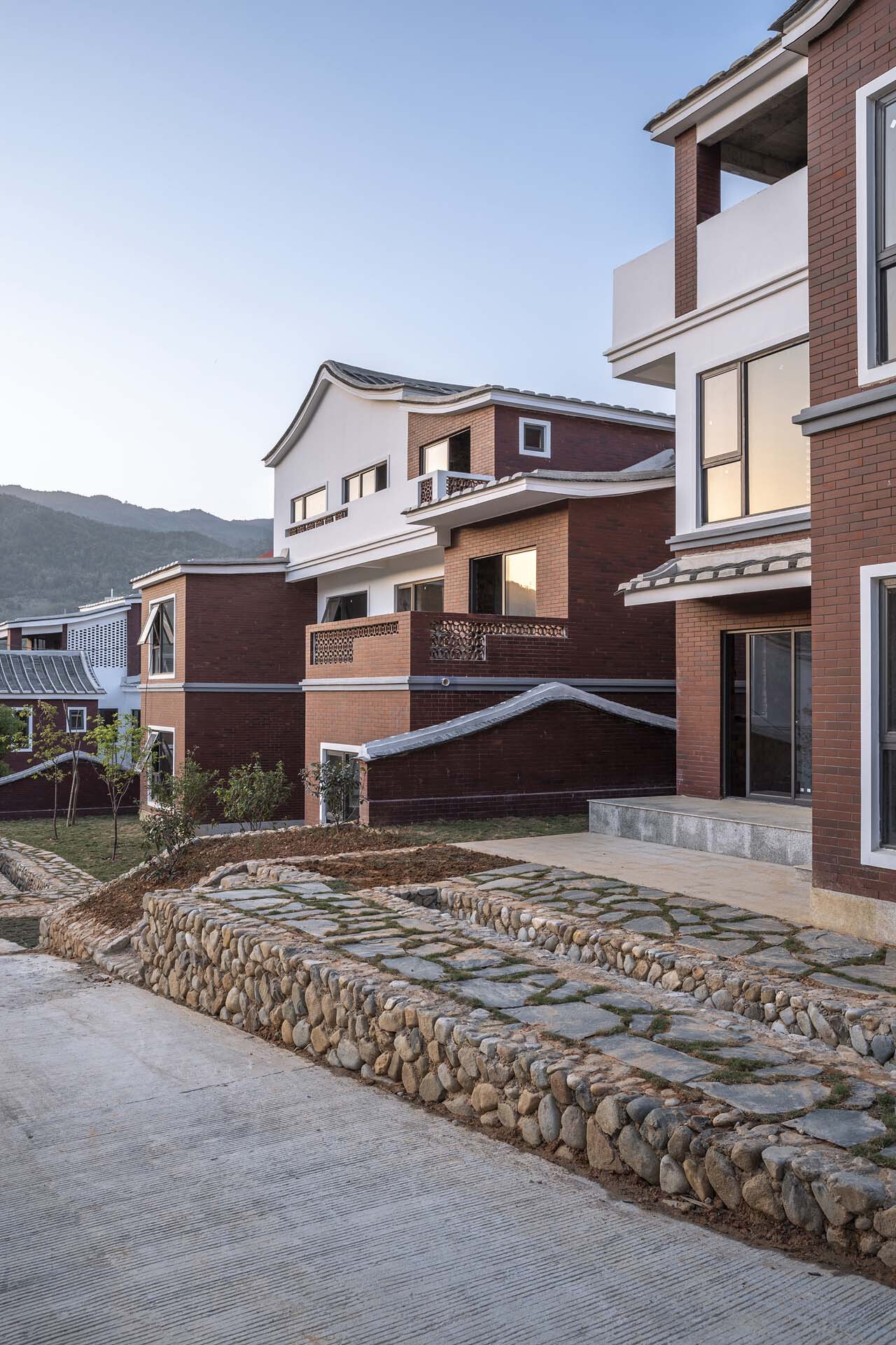 Stone-edged terraced courtyard with brick houses and mountains visible at dusk