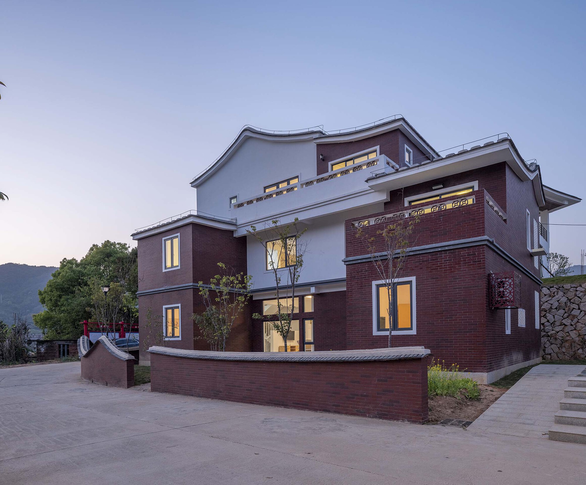 Multi-story red brick and white stucco facade with illuminated windows at dusk