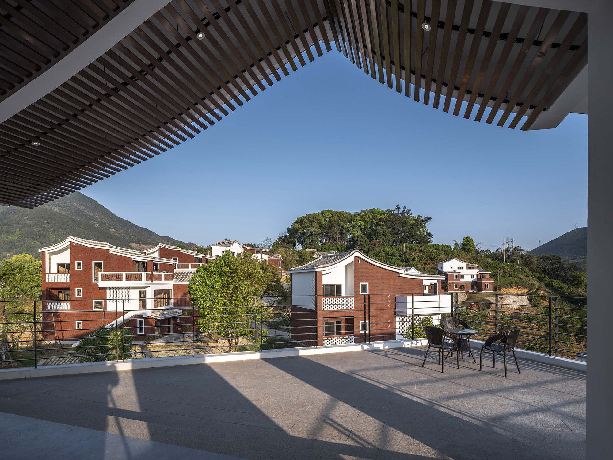 Roof terrace with slatted timber pergola framing a view of the residential cluster
