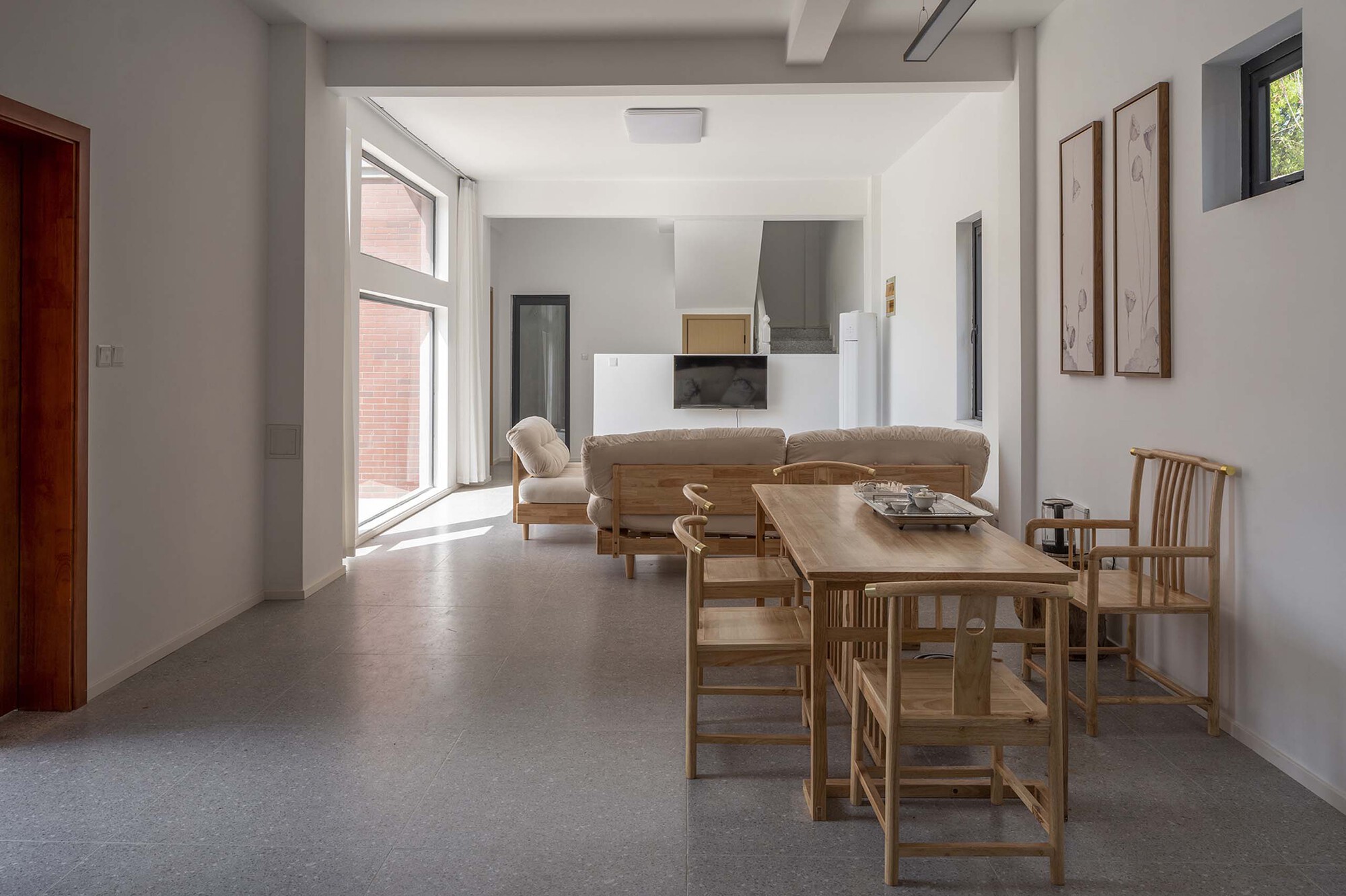 Open living and dining area with timber furniture and white walls under natural daylight