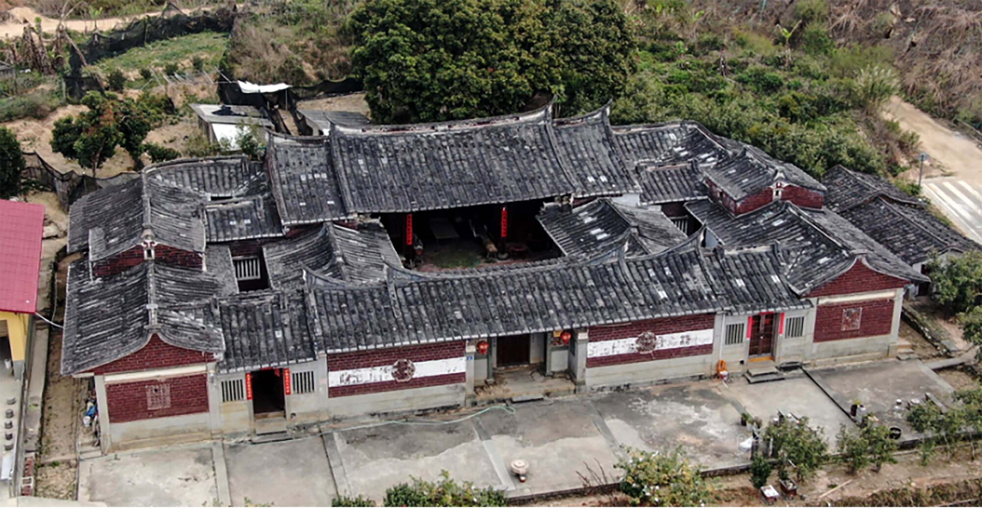 Aerial view of a traditional courtyard house with dark tiled roofs enclosing a central open space