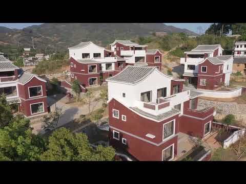 Aerial view of red brick houses with white accents and corrugated metal roofs on a hillside