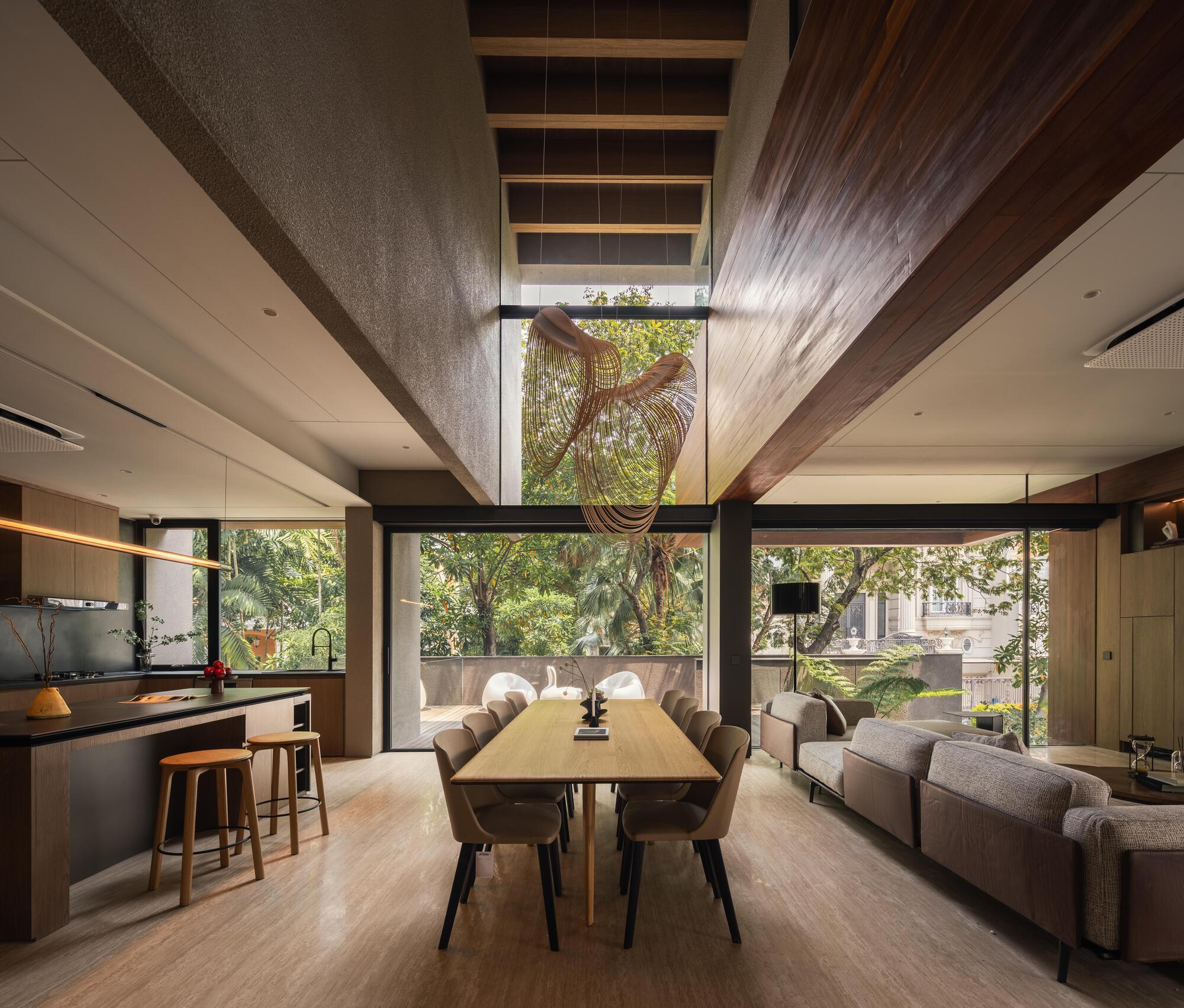 Open-plan living space with wood ceiling beams and floor-to-ceiling windows overlooking garden