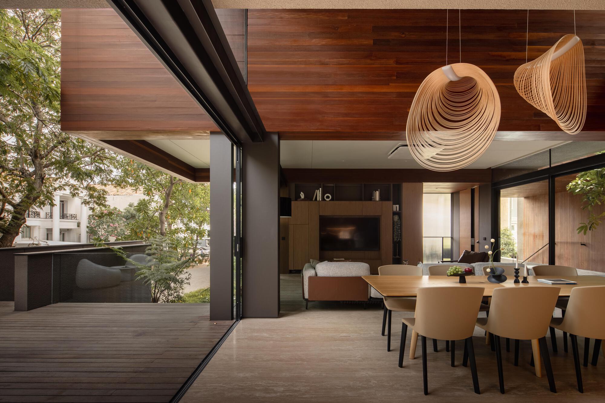 Dining area with folded pendant lights opening to a timber deck through sliding glass doors