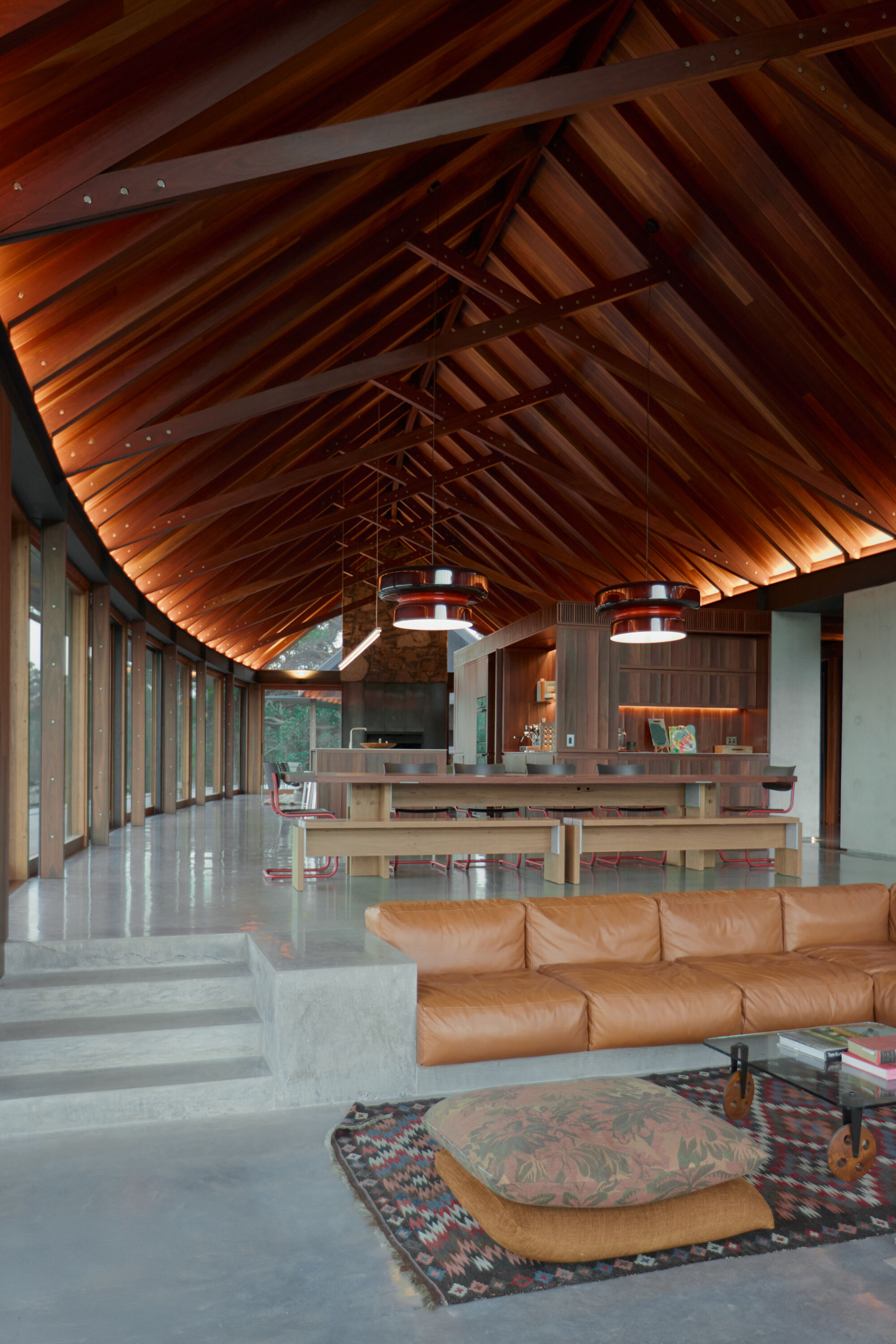 Open living space with exposed timber ceiling structure and polished concrete floor under vaulted roof
