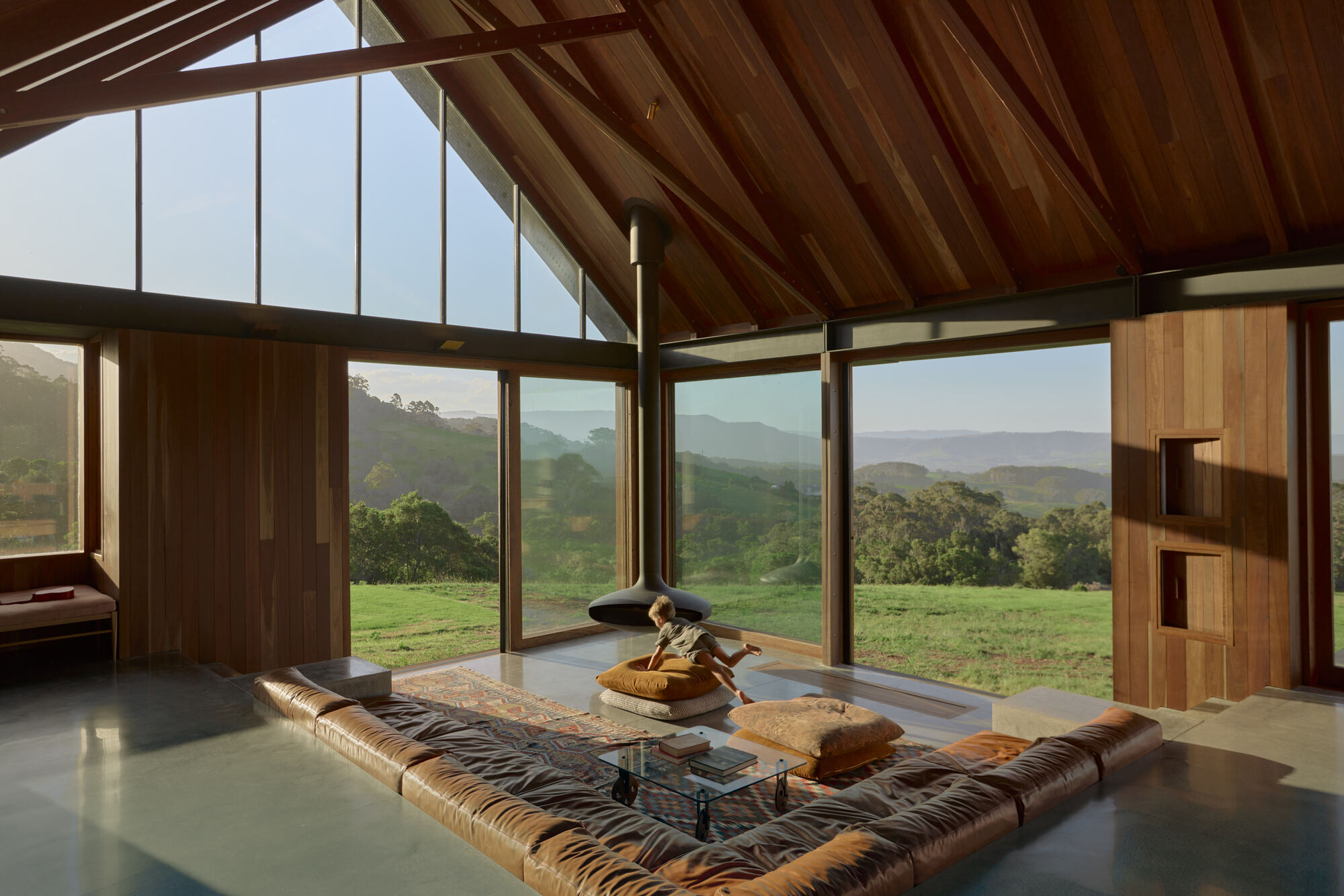 Living space with exposed timber ceiling beams and clerestory windows overlooking a green valley