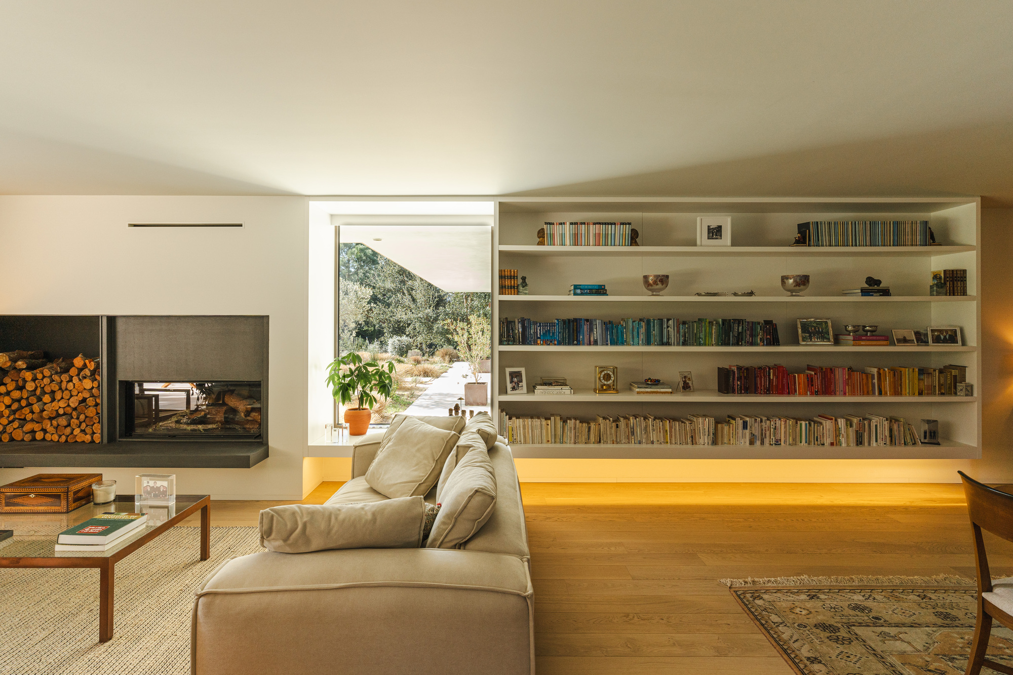 Living room with floor-to-ceiling bookshelves and fireplace framing a window view to the garden outside