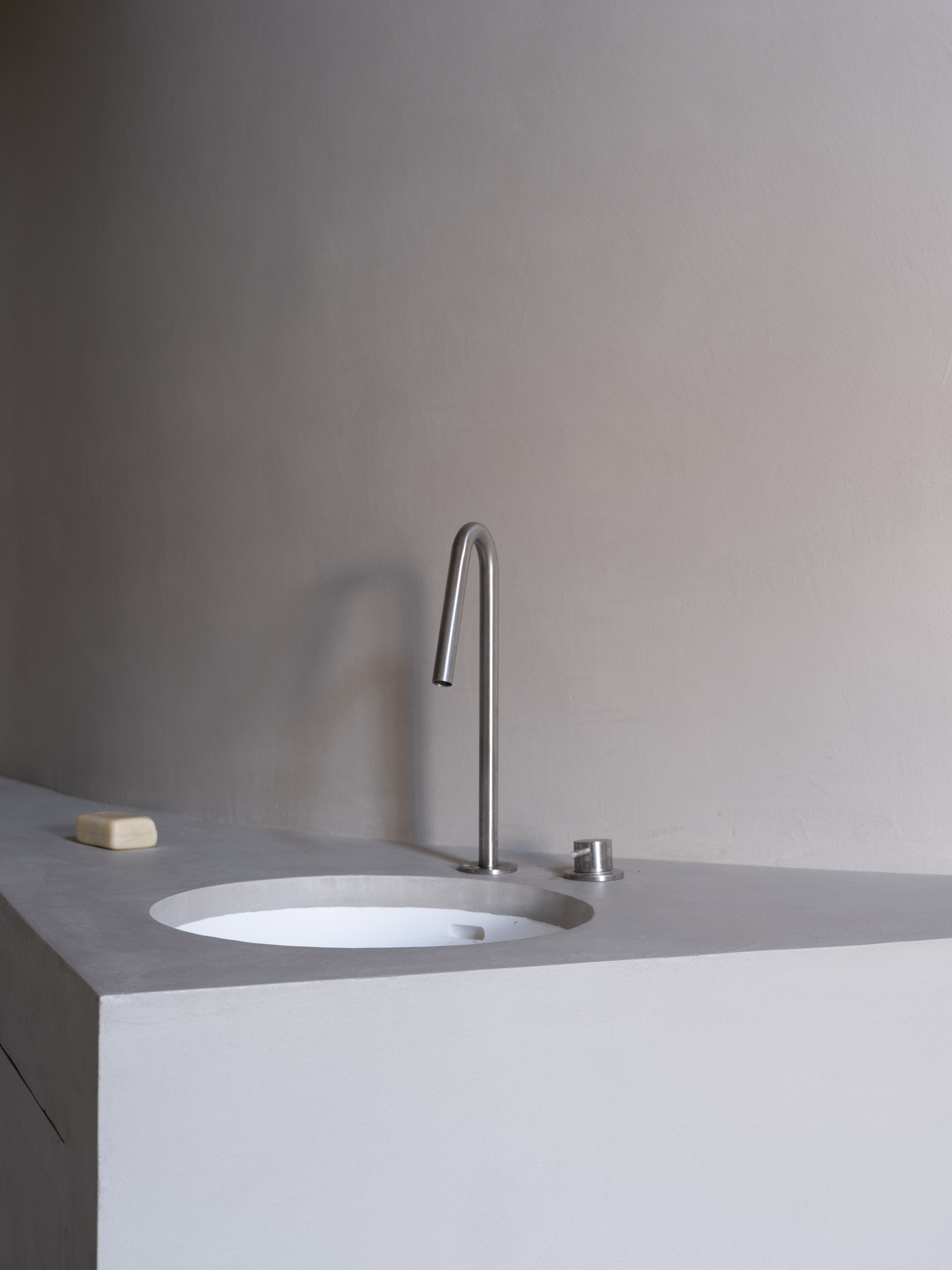 Close-up of integrated sink with high-arc tap and push button drain in pale grey countertop