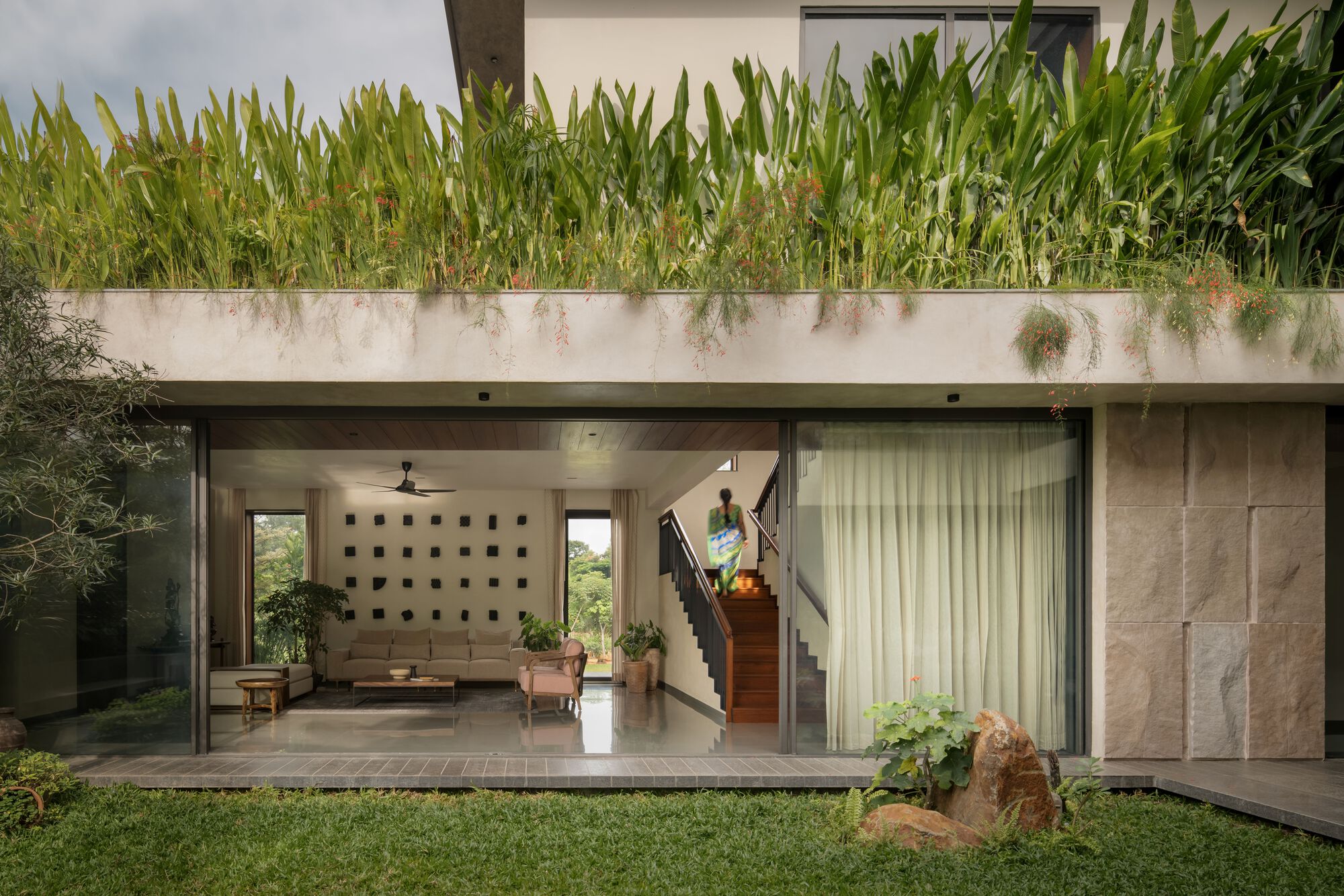 Ground floor interior opening to courtyard through sliding glass doors with planted rooftop terrace above