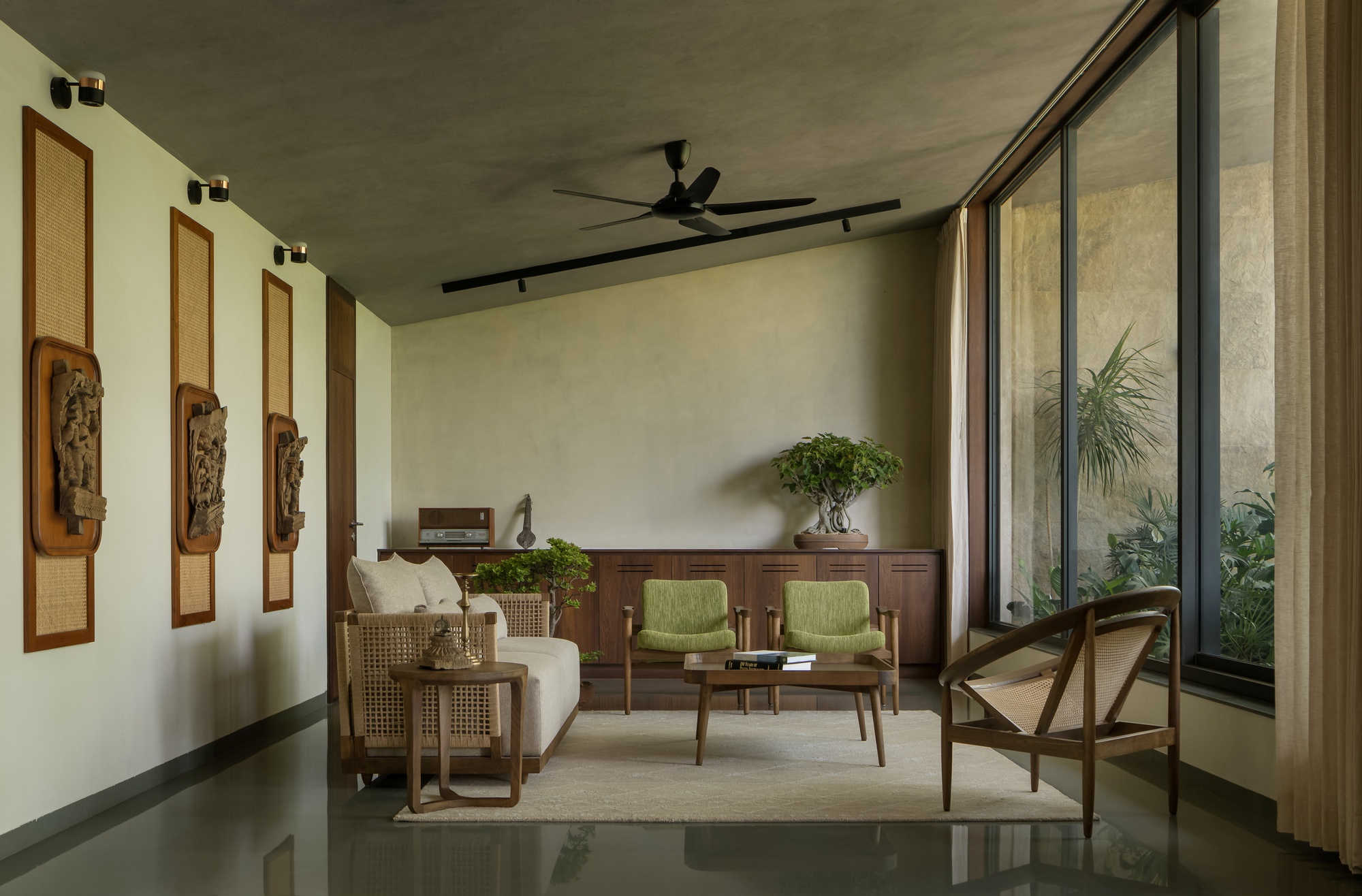 Living room with concrete ceiling, polished floor and full-height glazing overlooking internal garden
