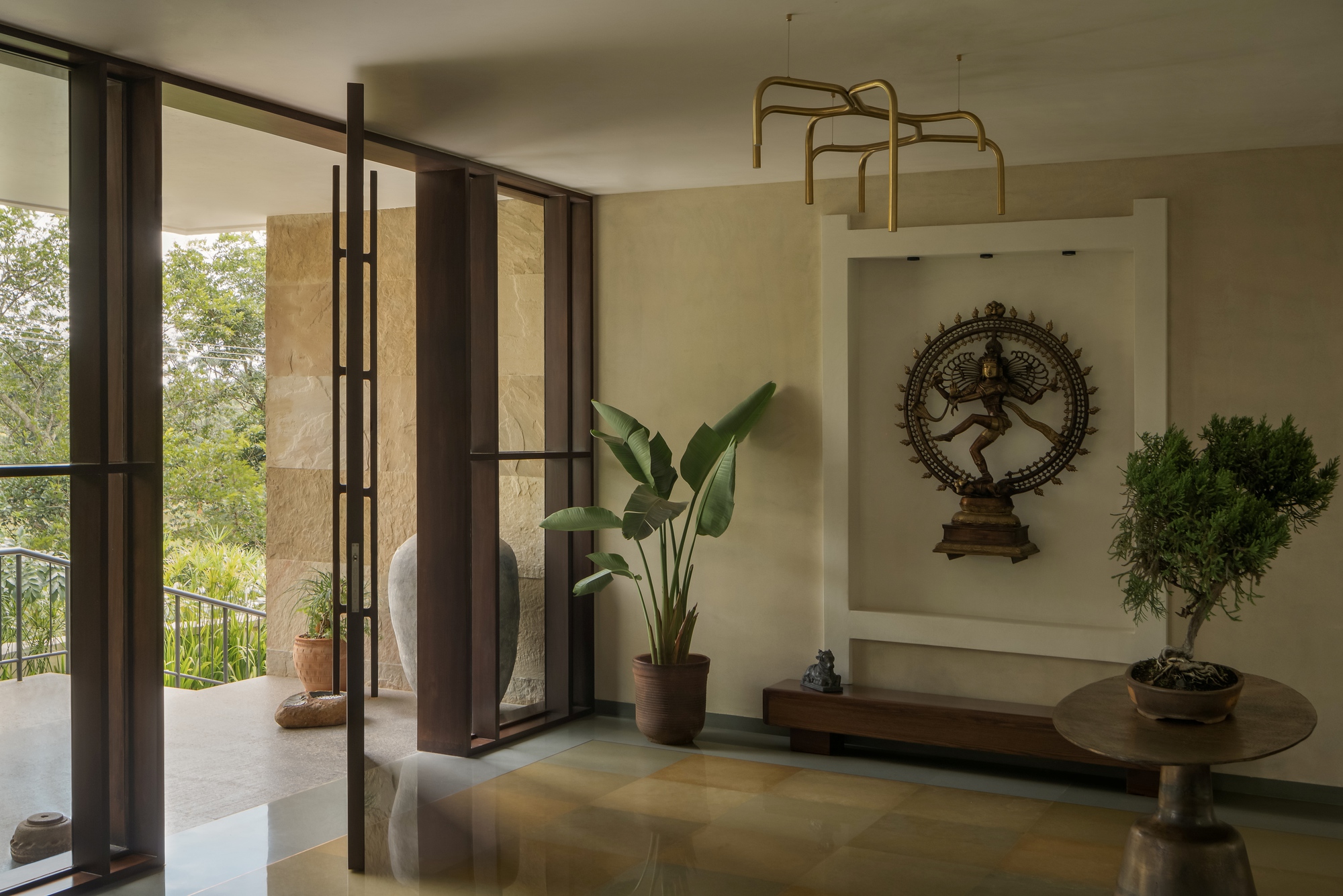 Meditation nook with pivoting steel-framed doors and display alcove for bronze sculpture flanked by potted plants