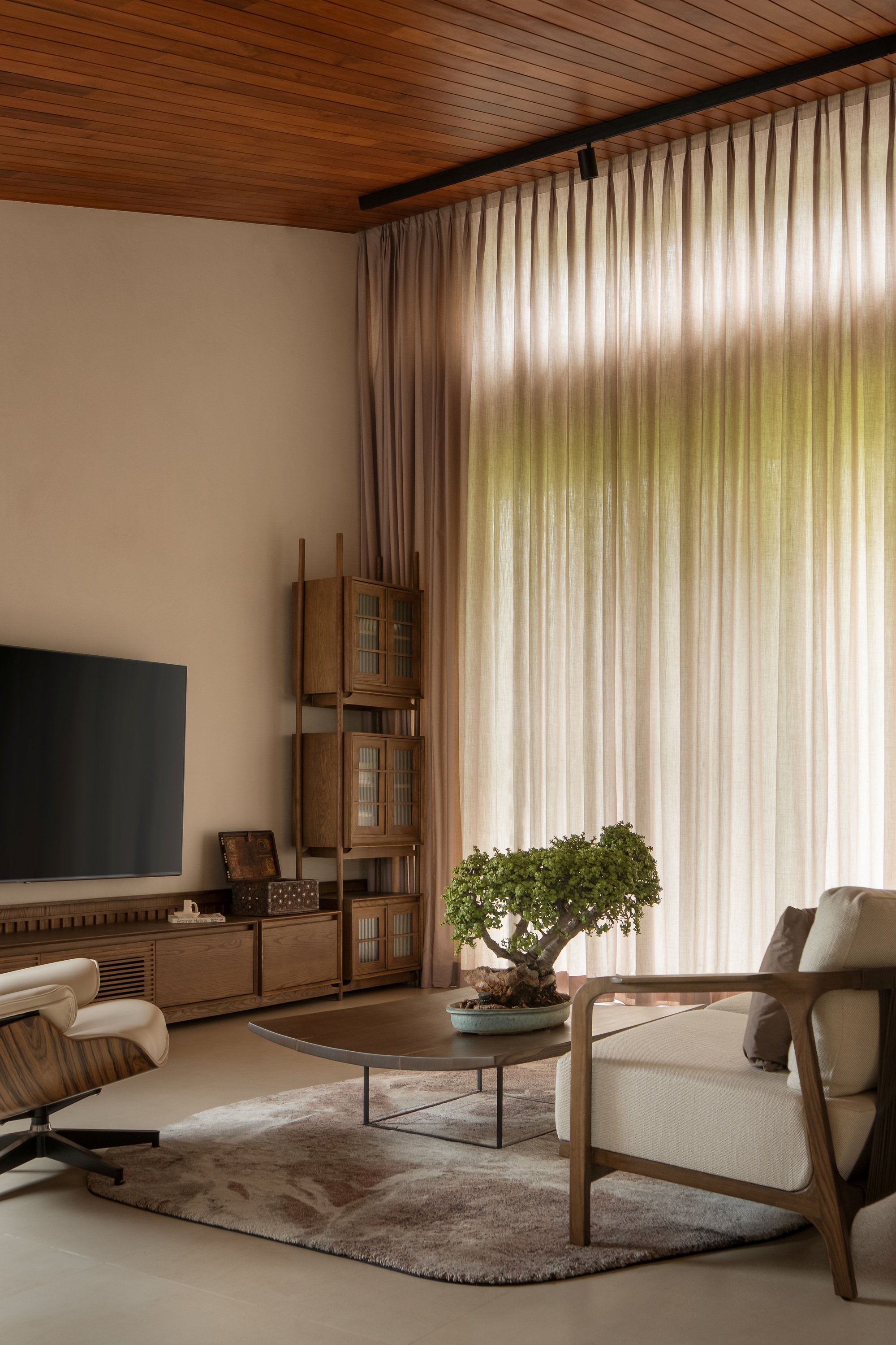 Living room with slatted wood ceiling, floor-to-ceiling sheer curtains filtering afternoon light