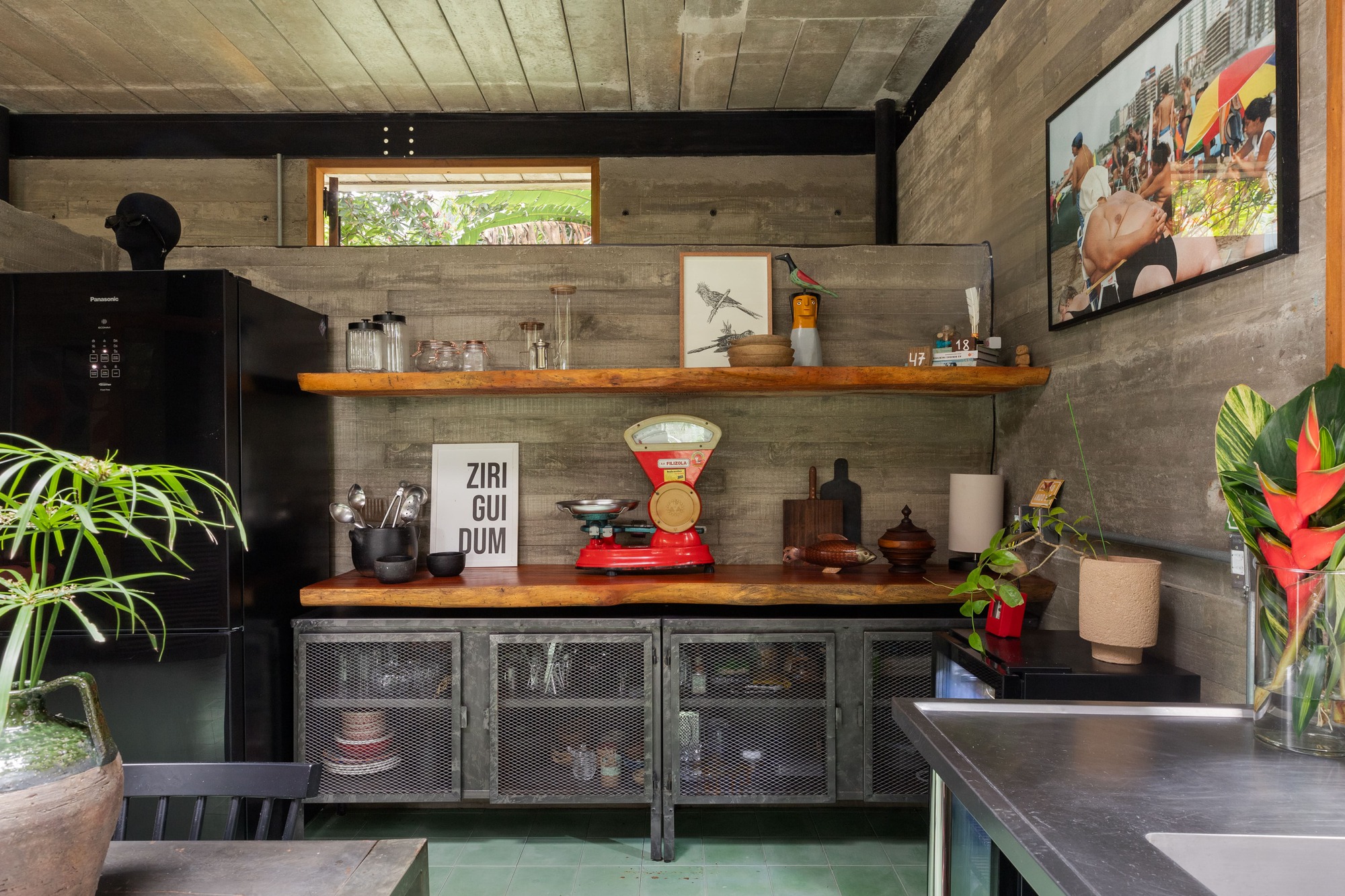 Kitchen area with open timber shelving and perforated metal cabinets below concrete walls