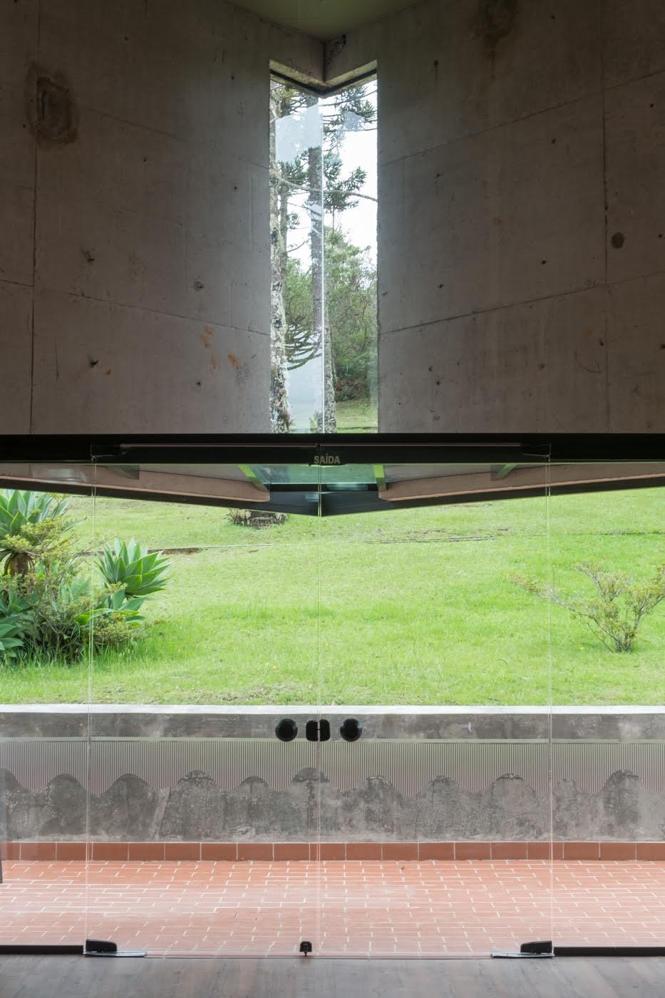 Corner window slot framing trees and lawn viewed from beneath a concrete ceiling and horizontal opening