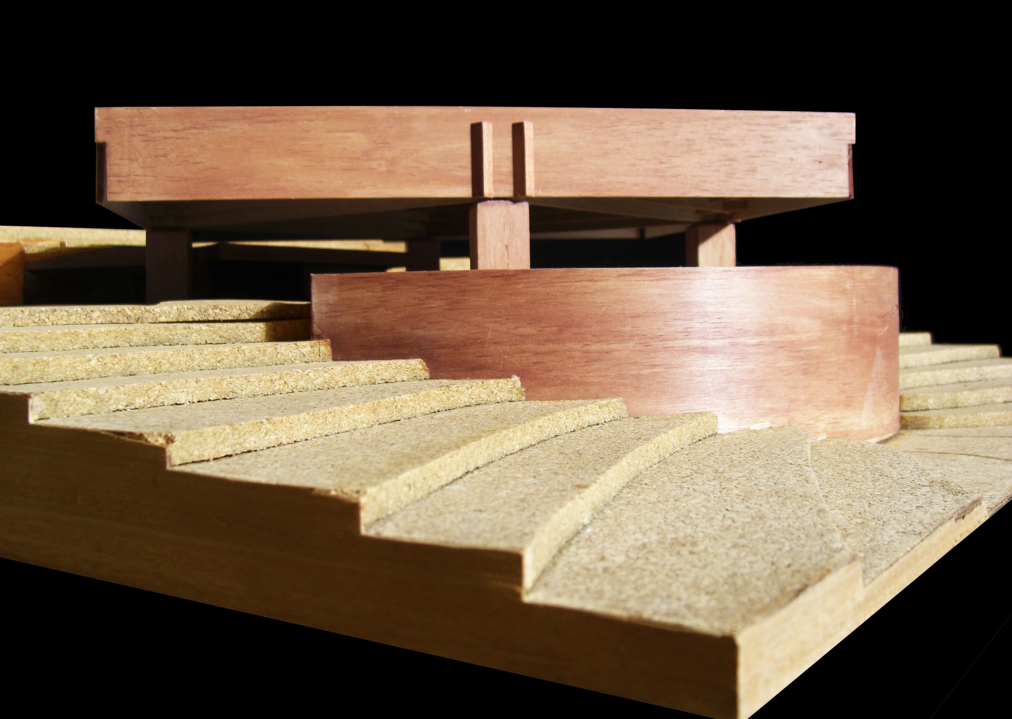 Close-up of the physical model showing timber columns supporting the raised volumes above stepped terrain
