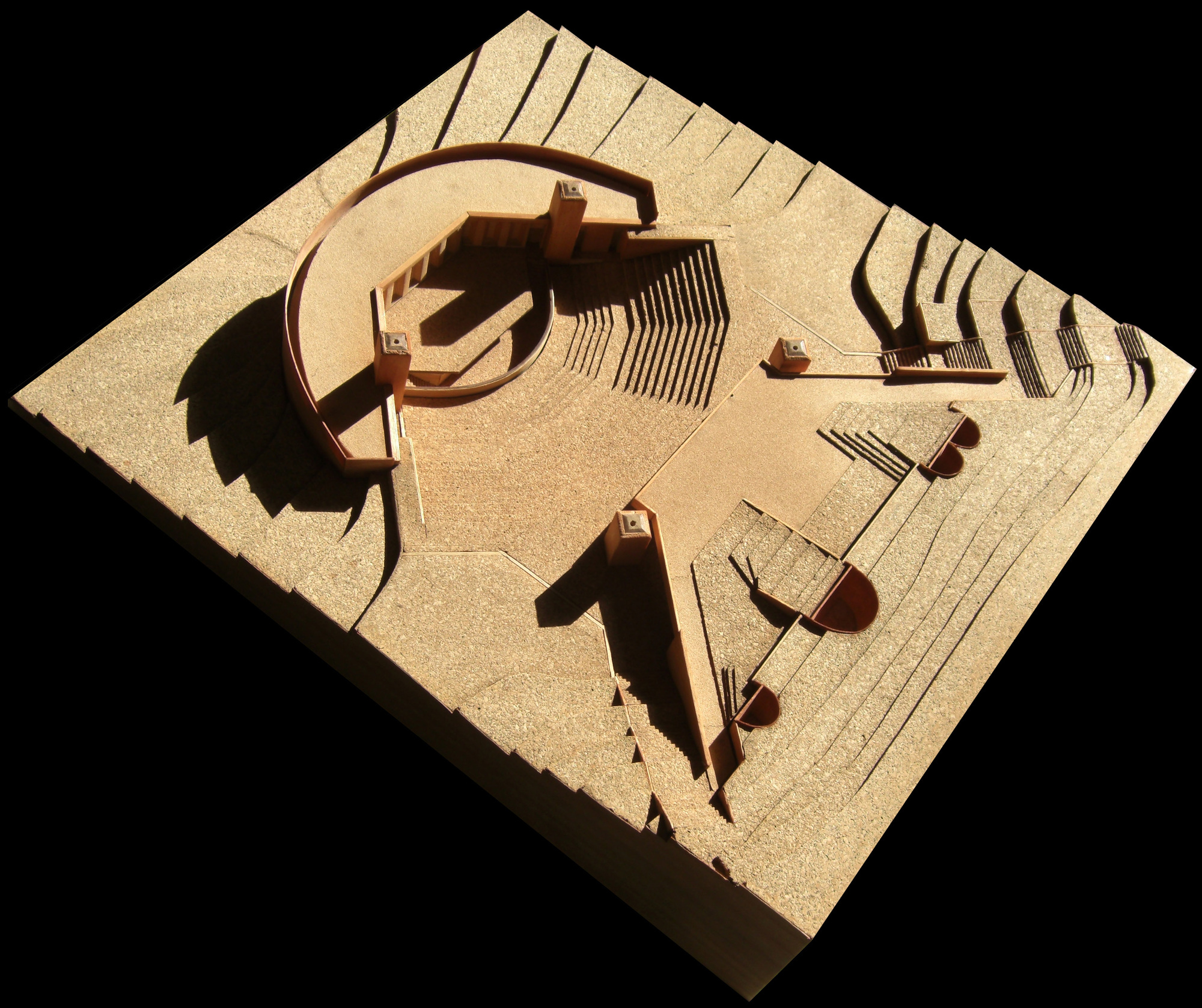 Aerial view of site model with curved retaining wall, tower, and tiered amphitheater casting shadows
