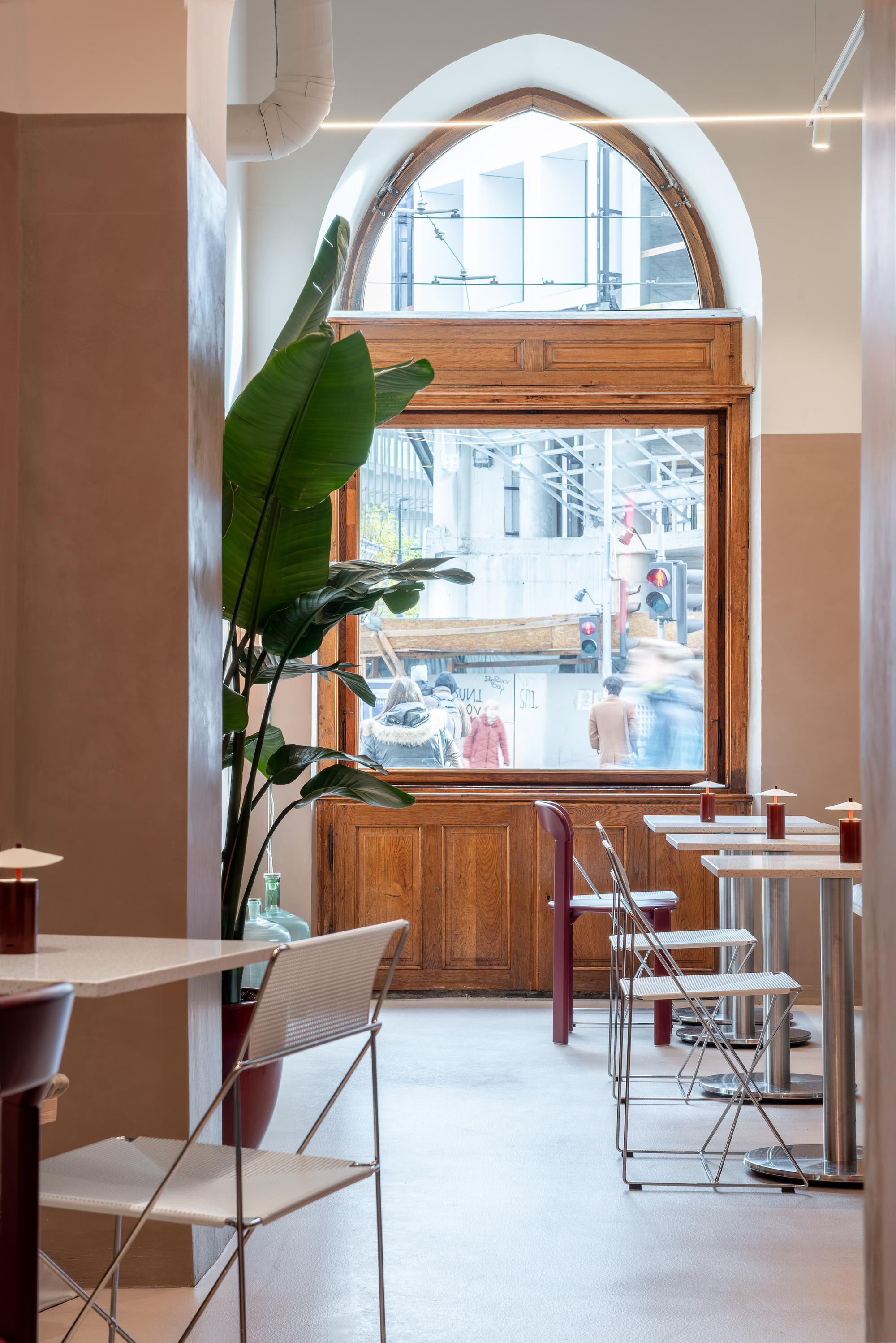 Arched opening framing wooden piano and potted banana plant with view to street beyond