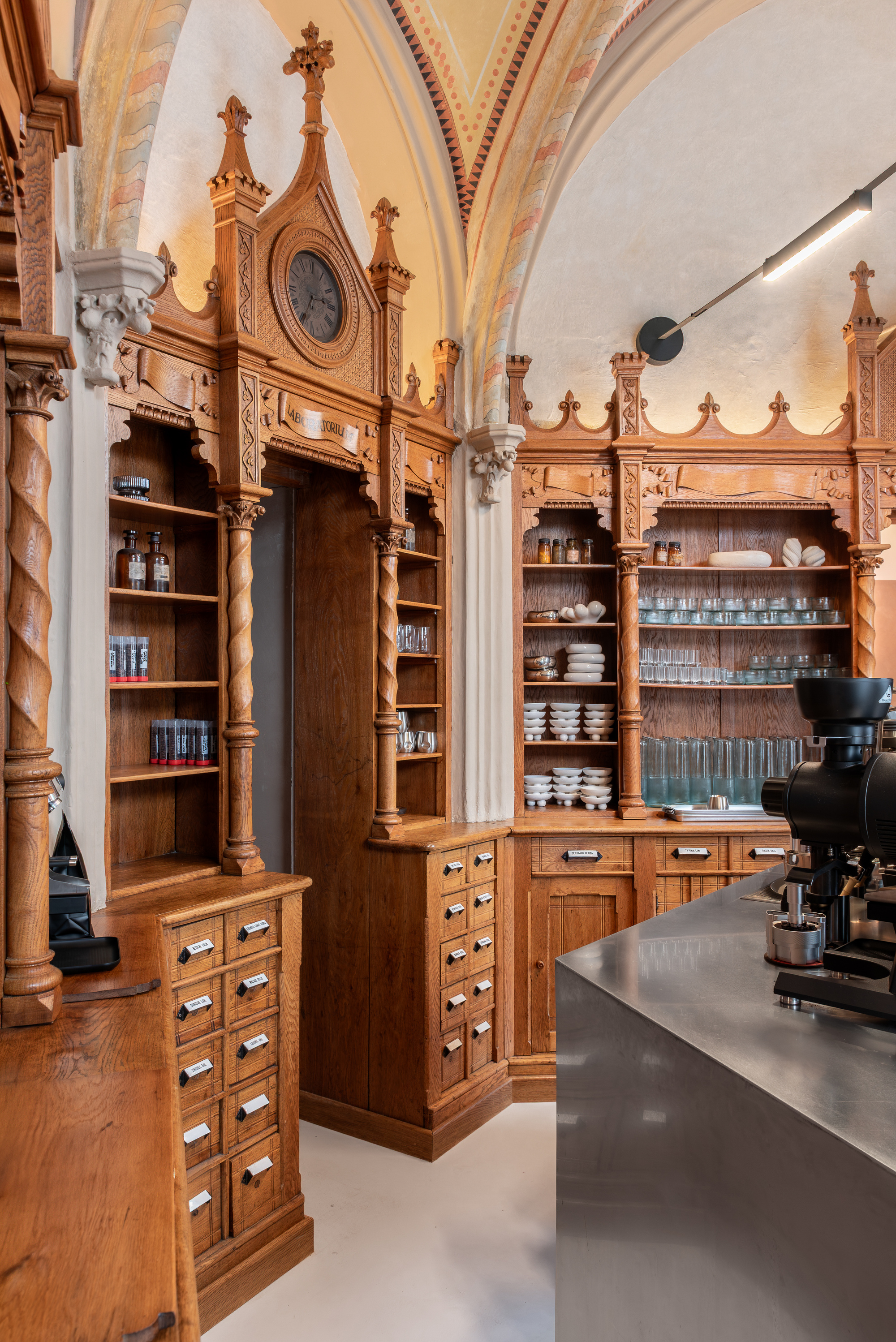 Timber cabinet with decorative Gothic arches and drawer units beneath groin vaulted ceiling