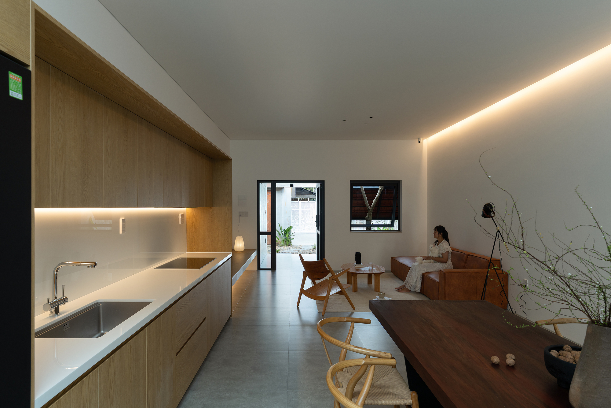 Open kitchen and dining area with timber cabinetry and a person seated in the distance