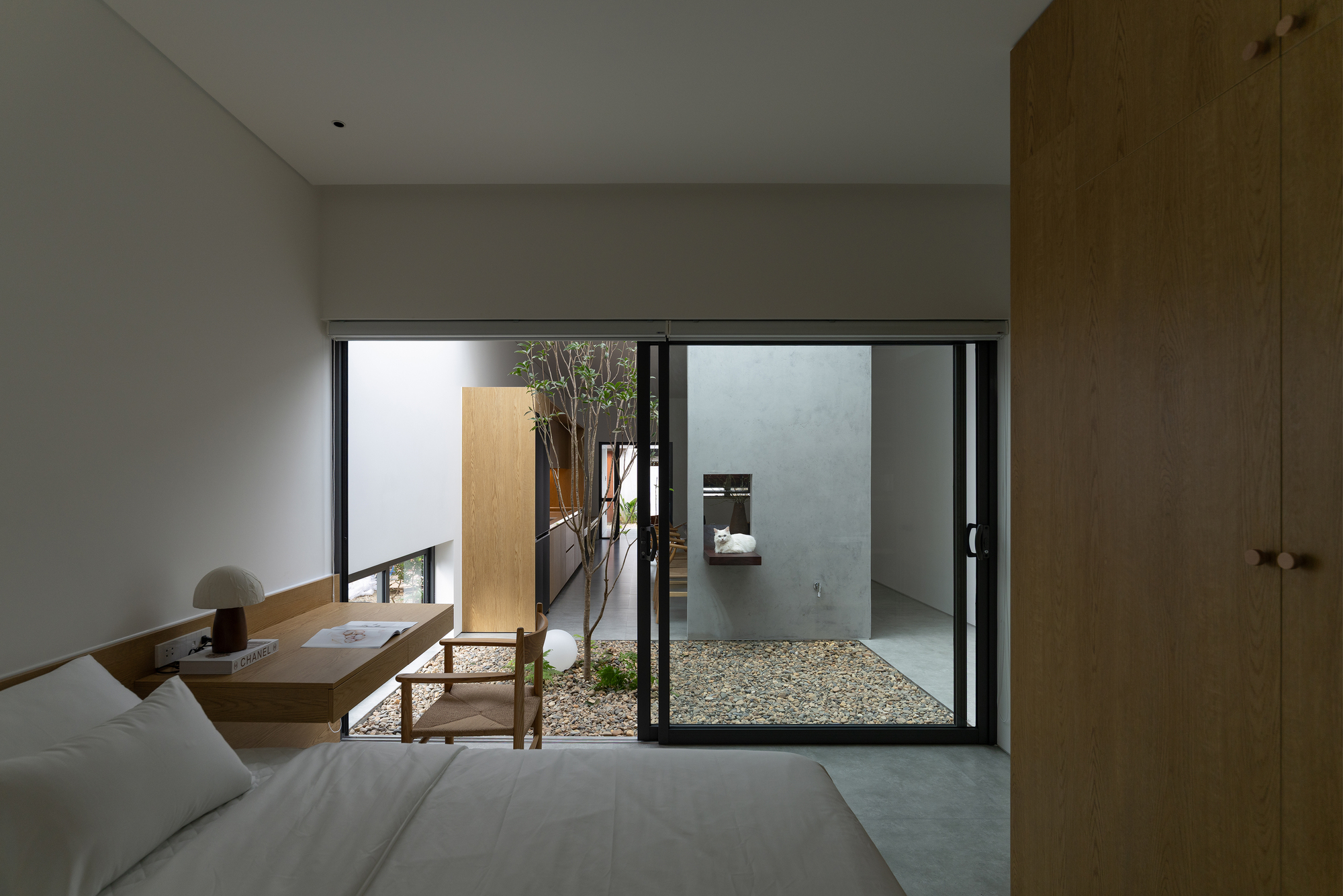 Bedroom view through sliding glass doors to internal courtyard with planted tree