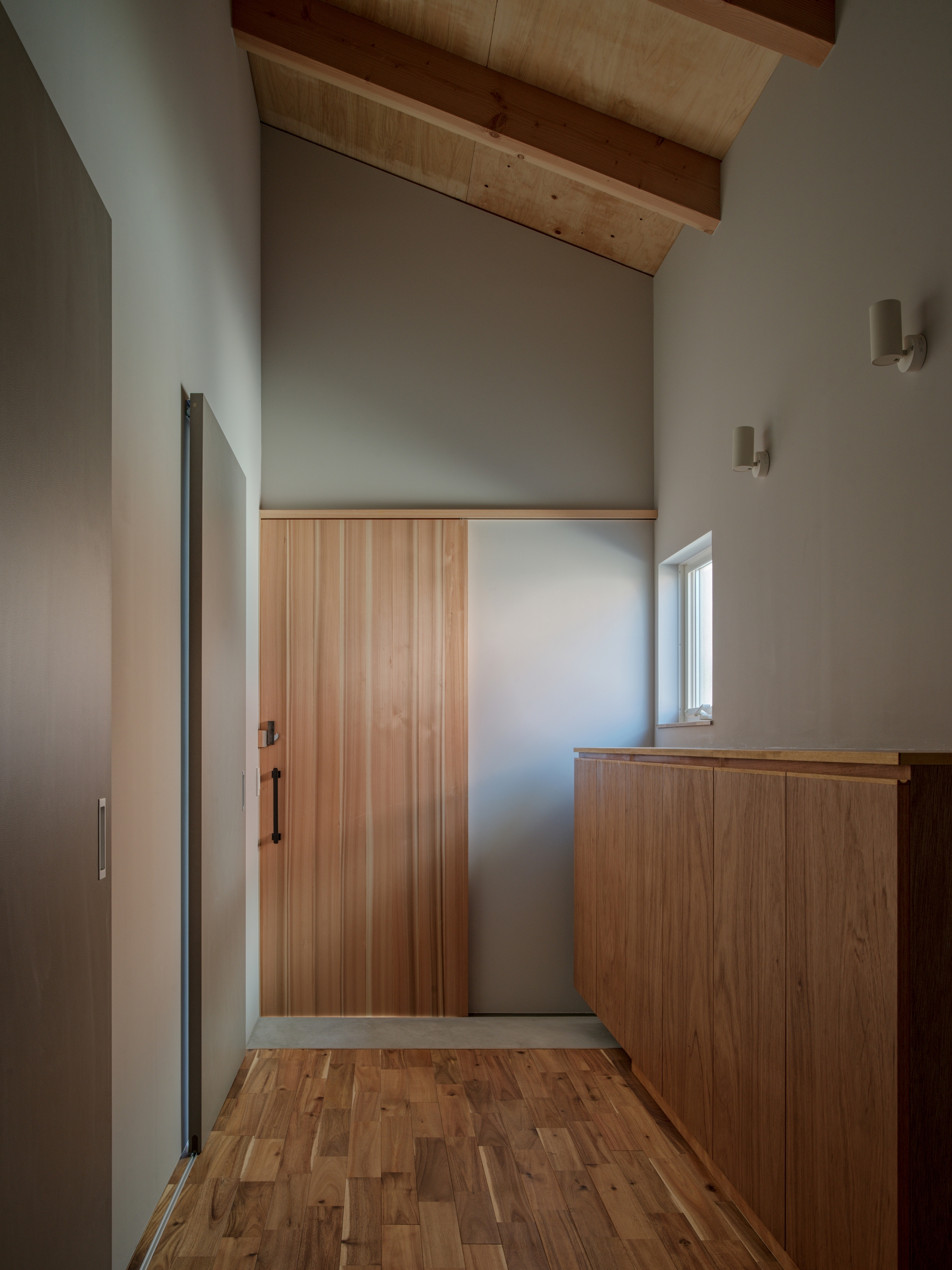 Entry hall with timber door and built-in cabinet under vaulted ceiling with exposed wood rafters
