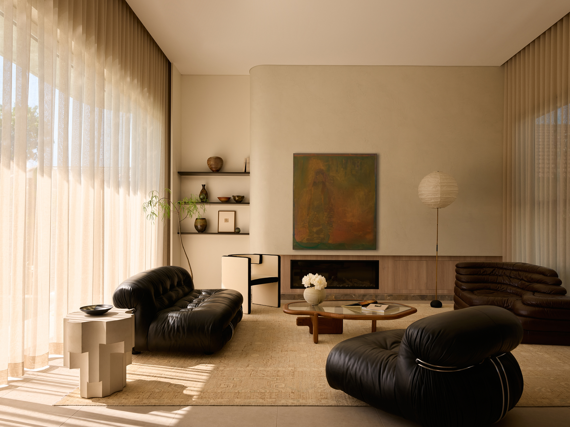 Living room with sheer curtains filtering afternoon light across timber cabinetry and built-in fireplace