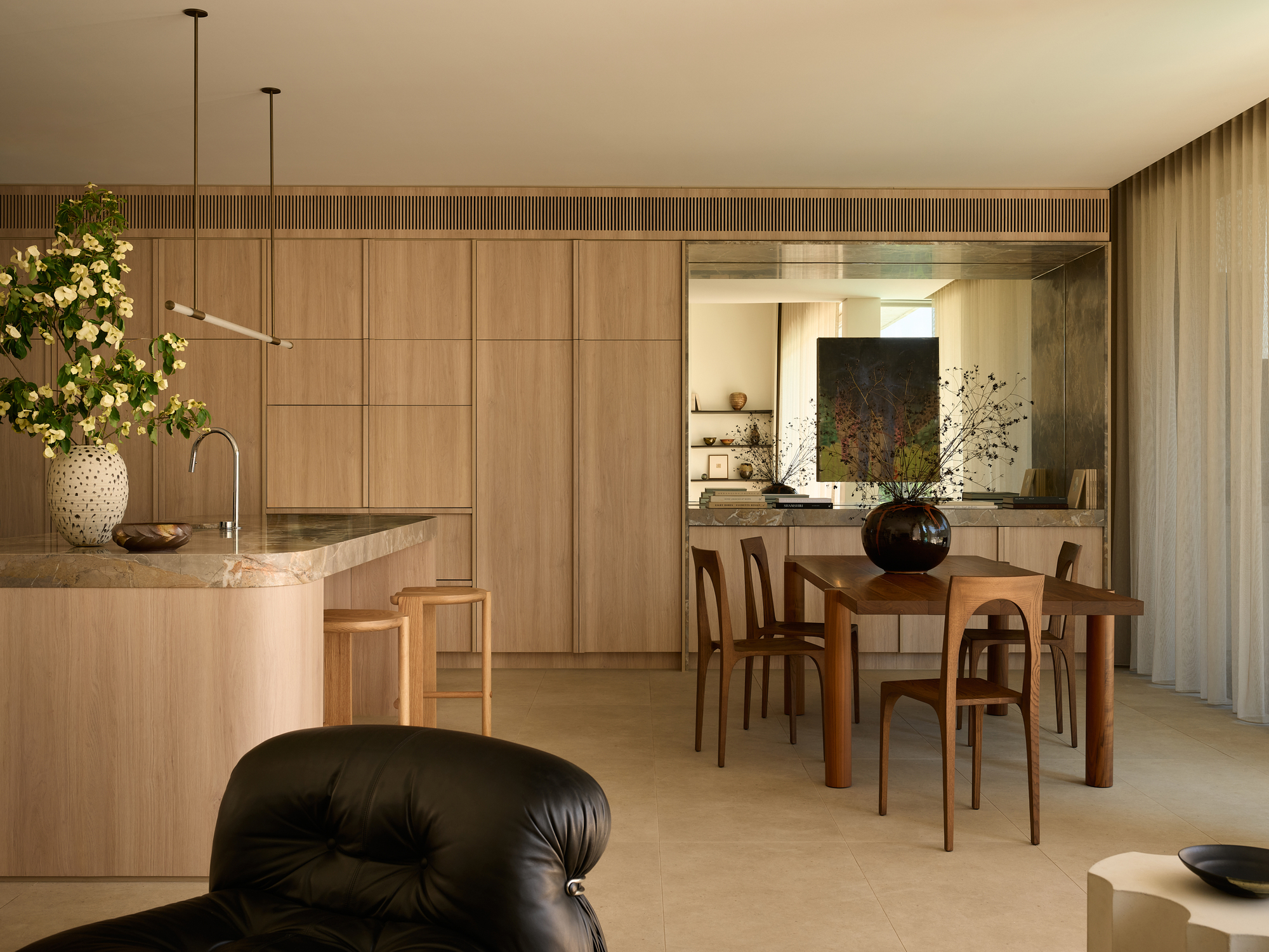 Open-plan kitchen and dining area with oak veneer cabinetry, stone benchtop and fluted timber ceiling detail