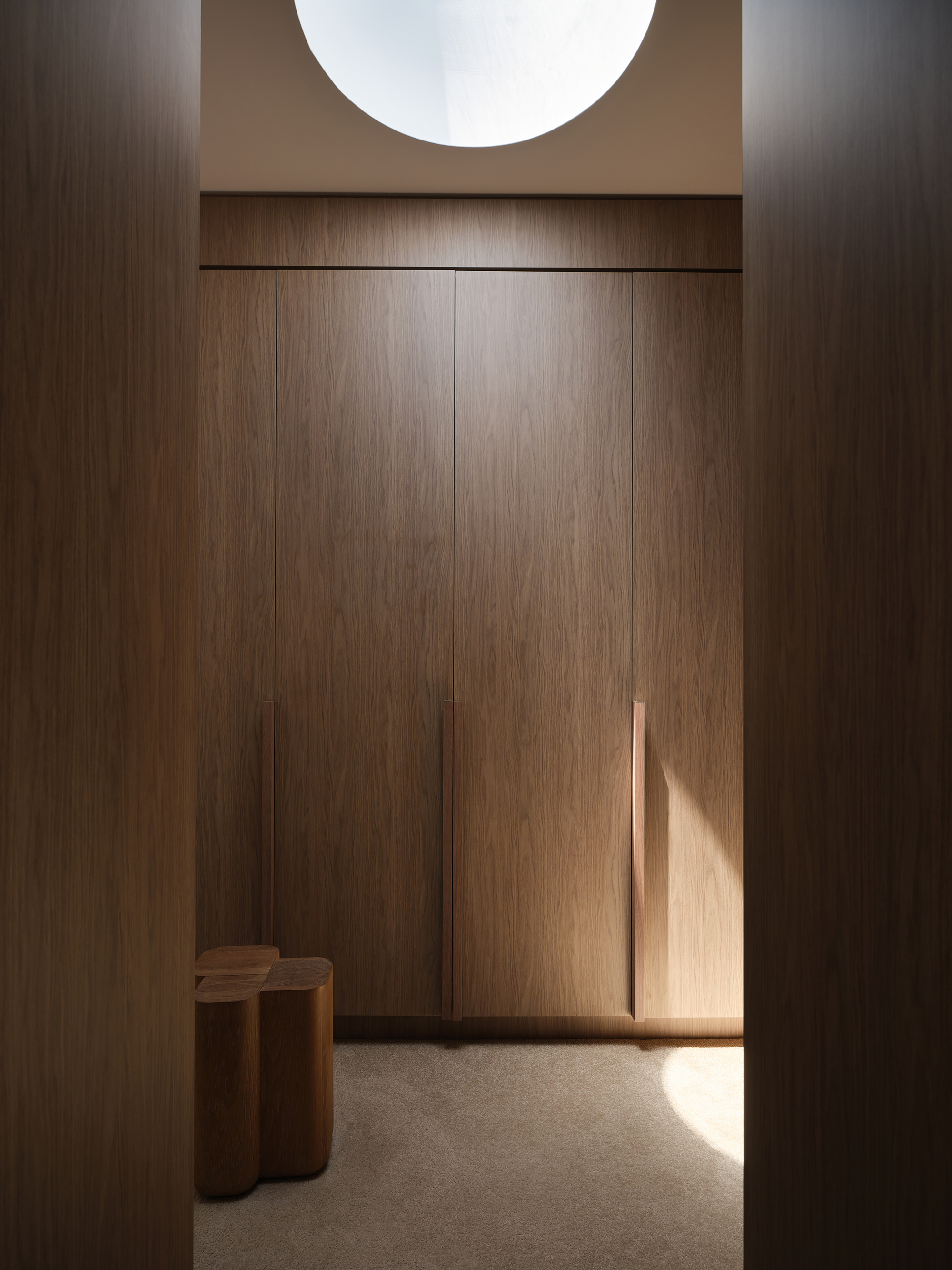 Timber-paneled entryway with recessed ceiling skylight and afternoon sunlight falling across the floor