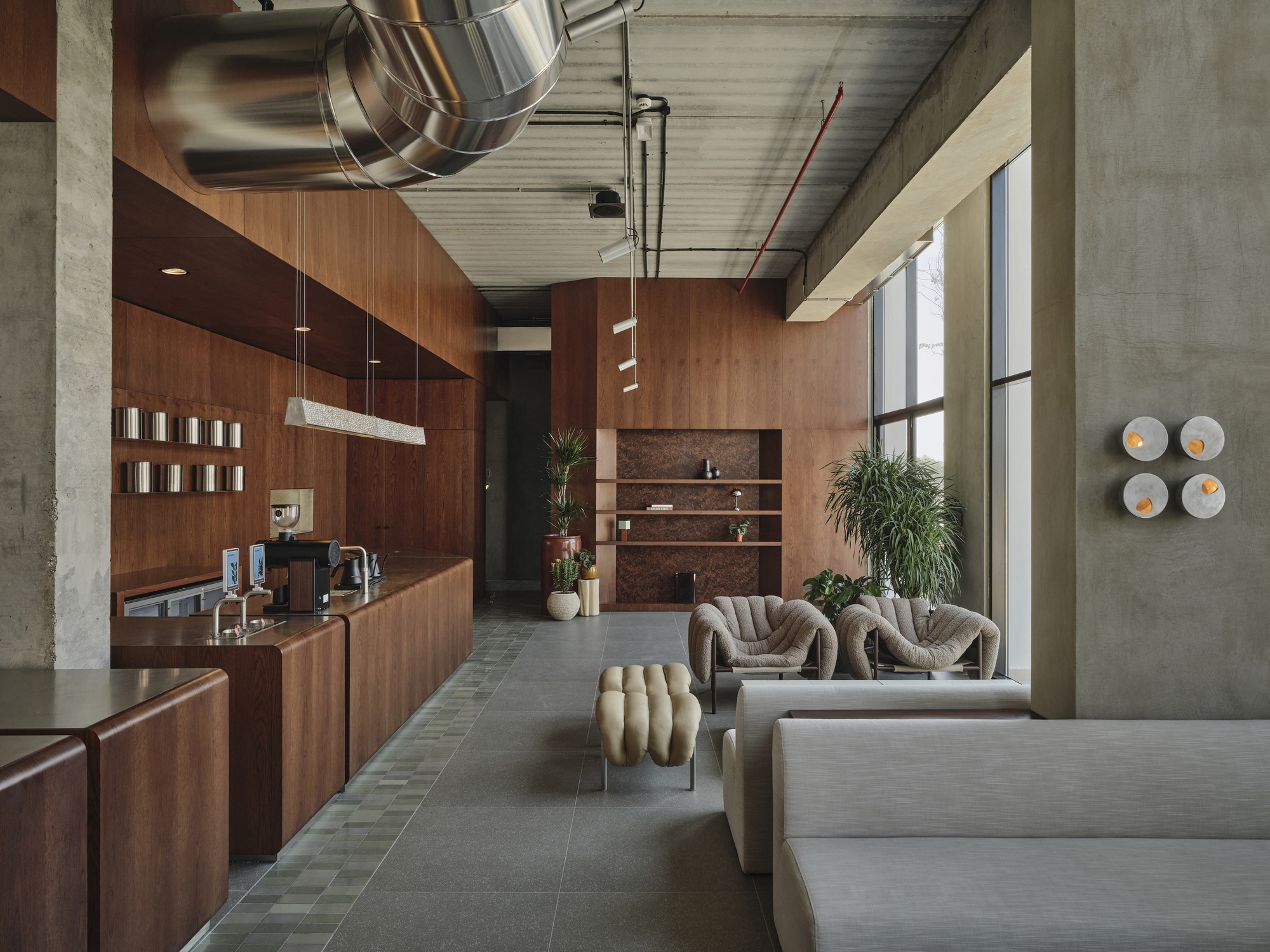 Reception area with walnut paneling and exposed concrete columns flanking gray tile floor